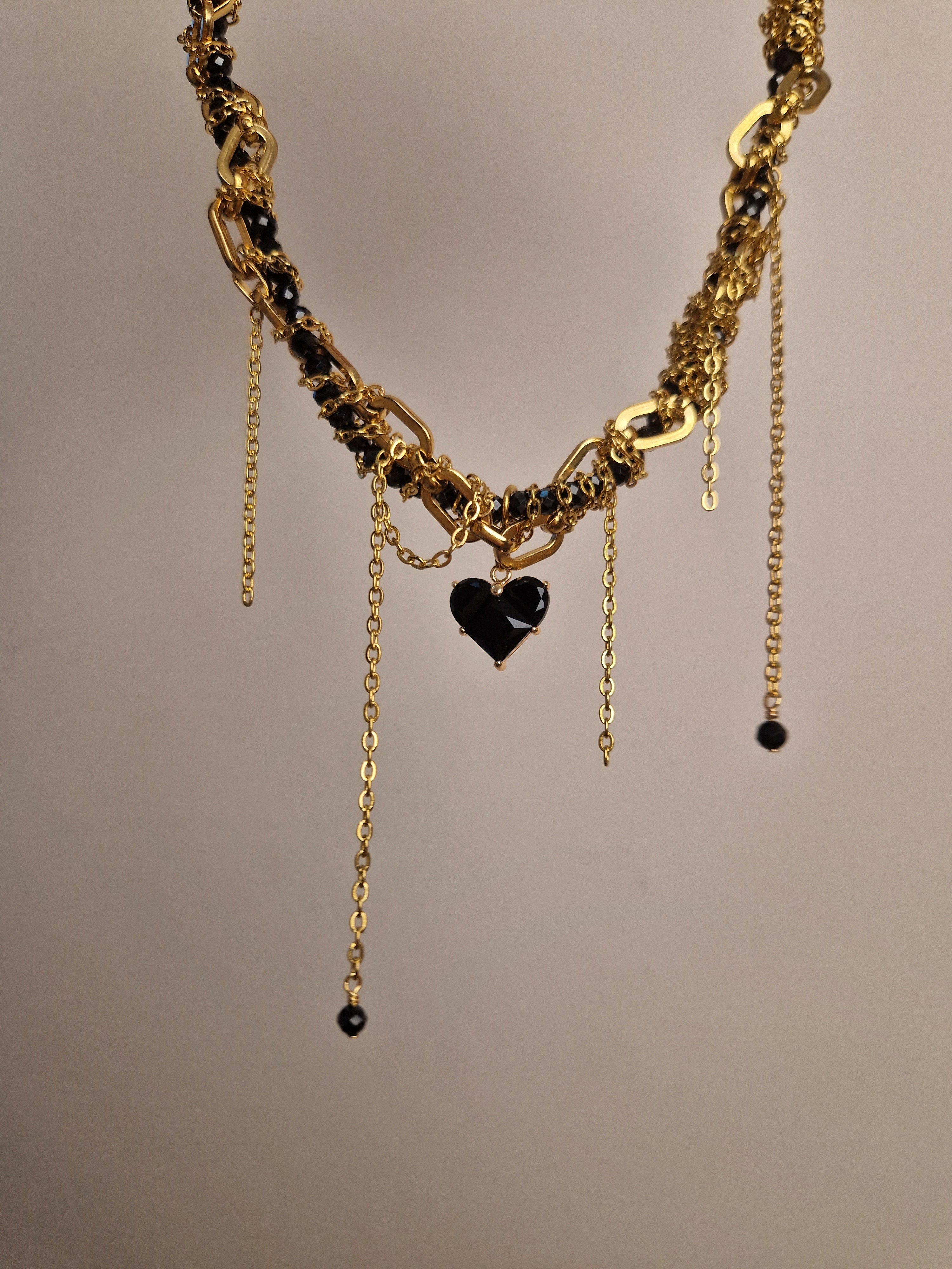 Gold-plated necklace with black heart pendants.