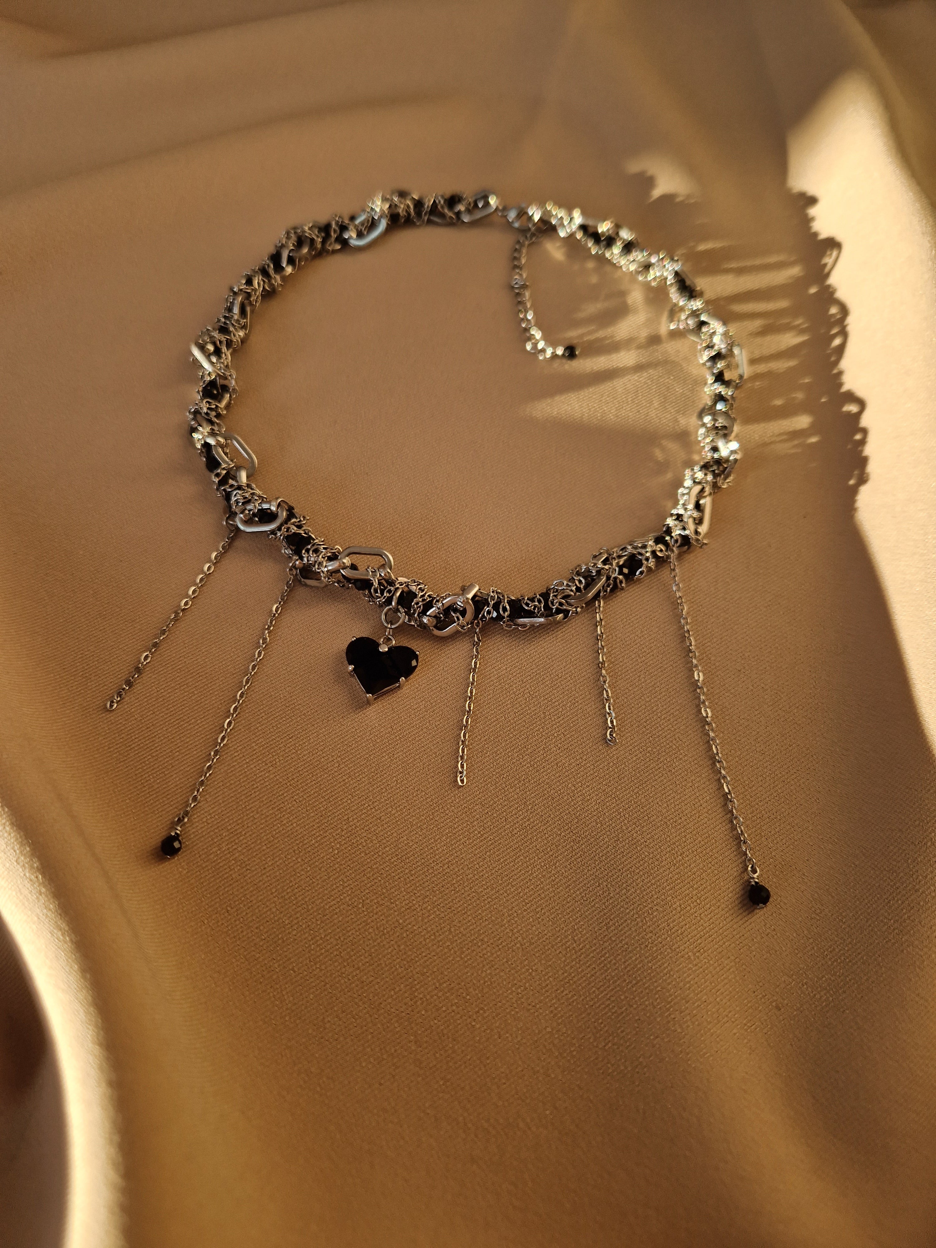 Striking silver-tone necklace featuring layered chains and sparkling black cubic zirconia stones, crafted from stainless steel and rhodium-plated brass for a modern, edgy look.