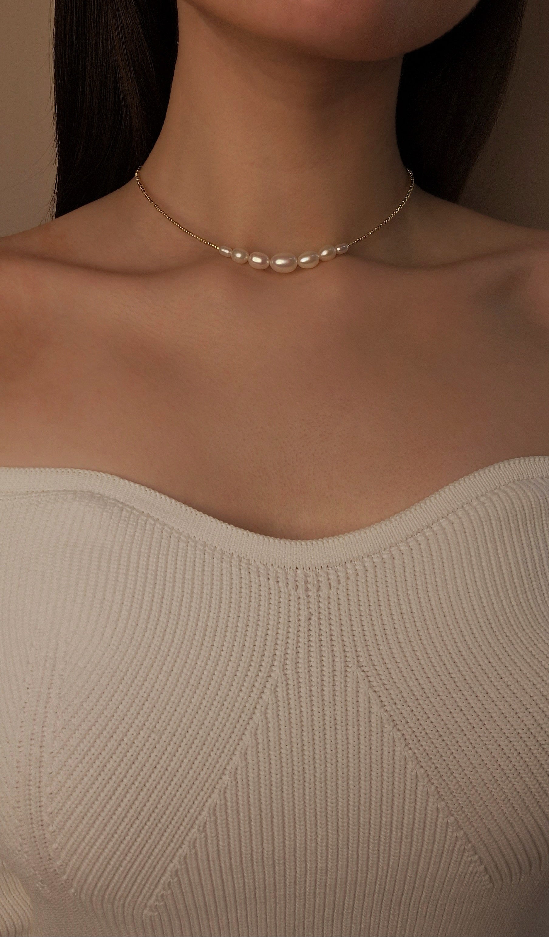 Pearl necklace with beaded worn by a person with a neutral background