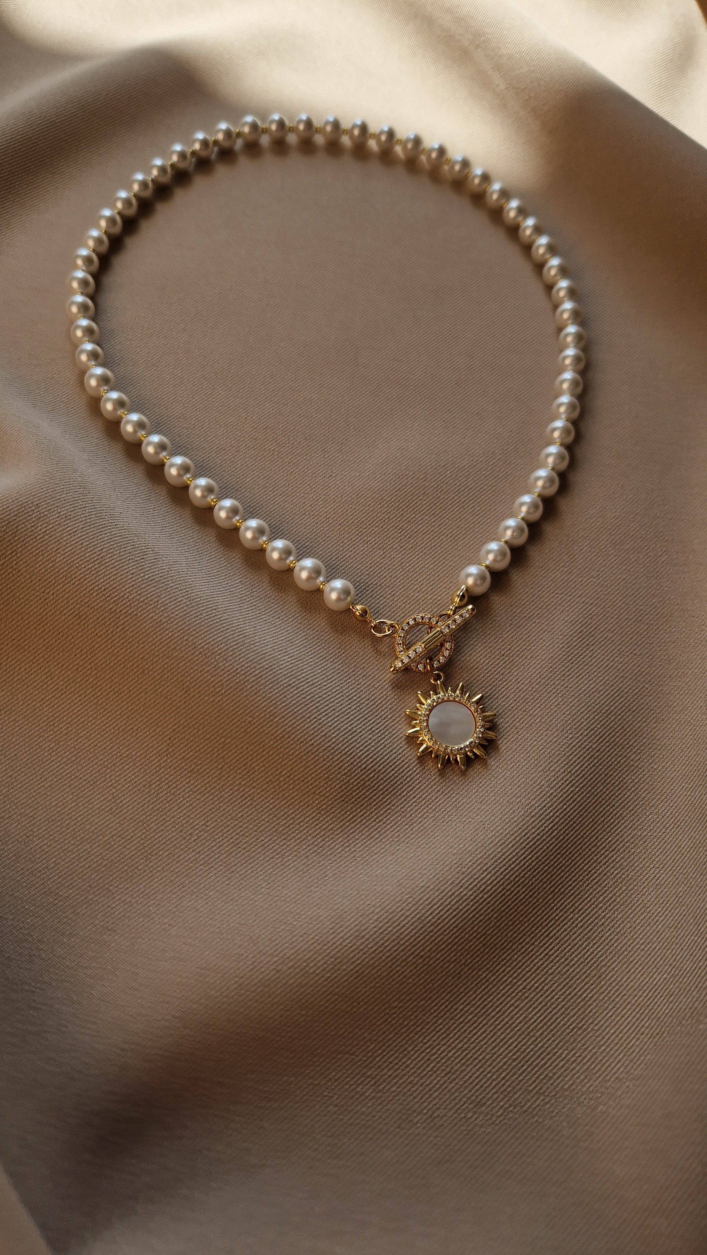 Pearl necklace with a gold-plated clasp on a beige fabric background