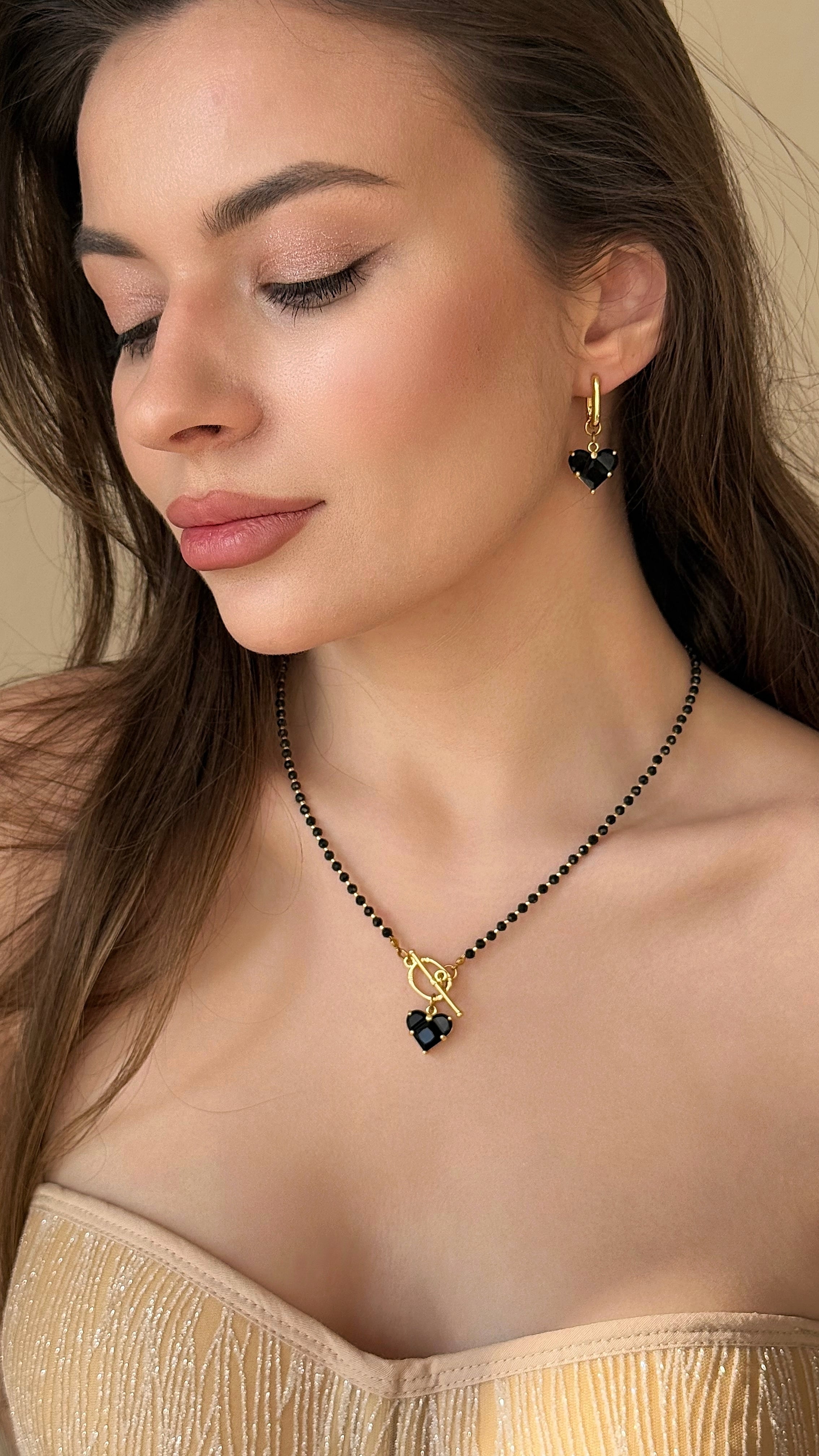 Woman wearing a necklace and earrings with a neutral background