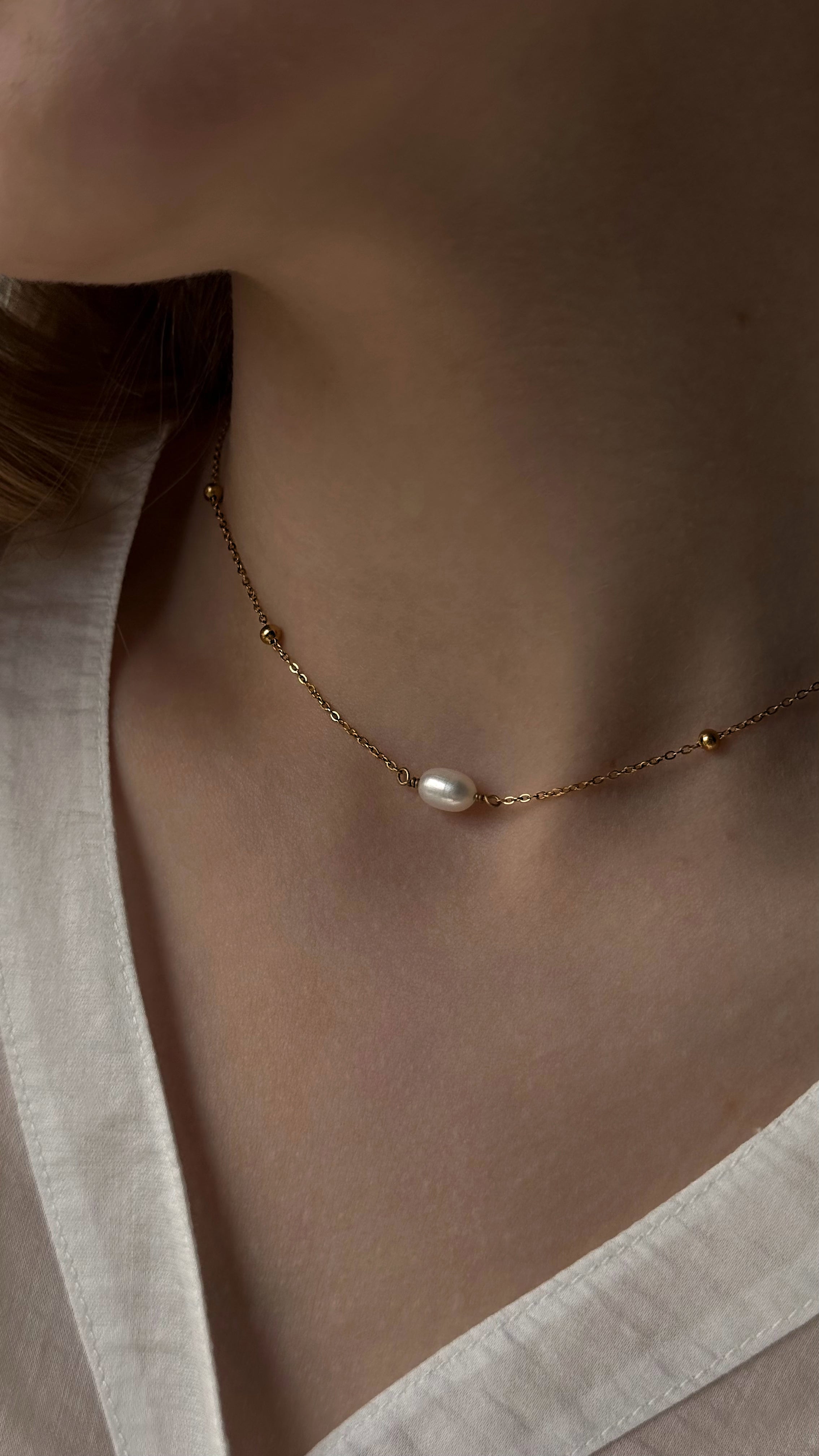 Minimalist gold-tone chain necklace featuring a single natural freshwater pearl. A sleek and elegant design perfect for everyday wear, combining timeless simplicity with modern style. Crafted from durable, hypoallergenic stainless steel for lasting comfort.