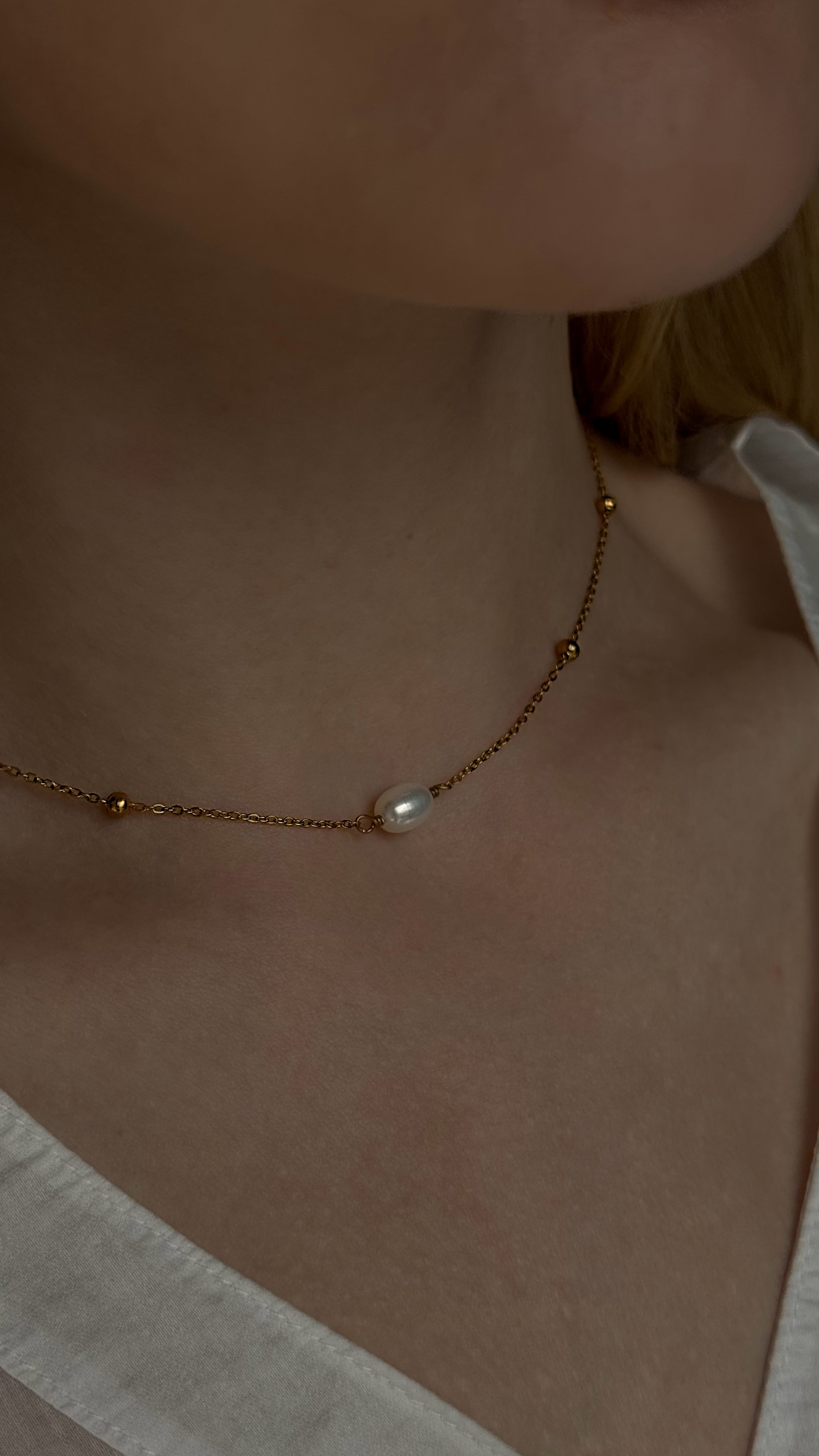 Minimalist gold-tone chain necklace featuring a single natural freshwater pearl. A sleek and elegant design perfect for everyday wear, combining timeless simplicity with modern style. Crafted from durable, hypoallergenic stainless steel for lasting comfort.