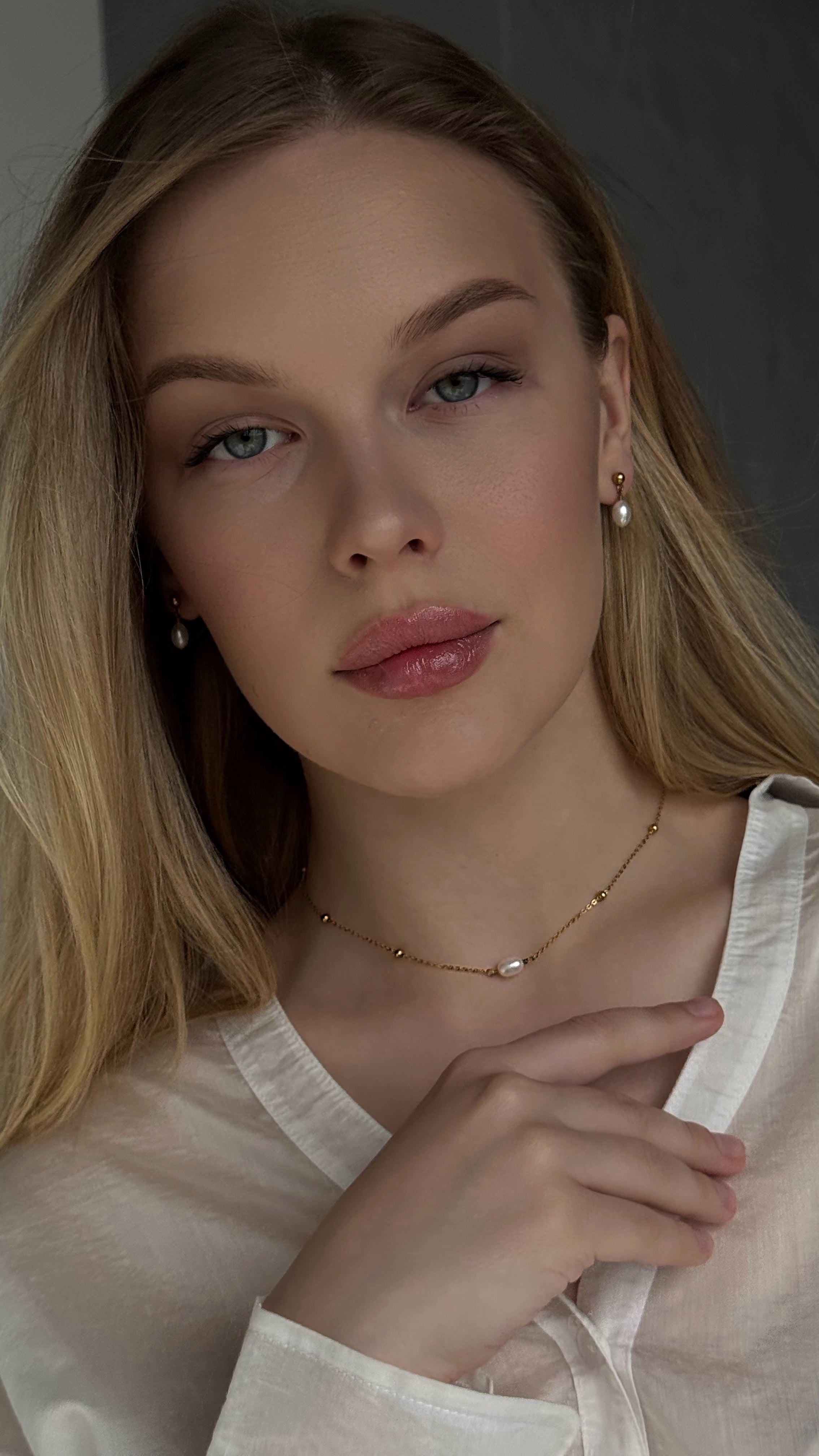 Stylish gold-tone stainless steel necklace with a single natural pearl pendant, paired with delicate natural pearl stud earrings, combining modern durability and timeless elegance.