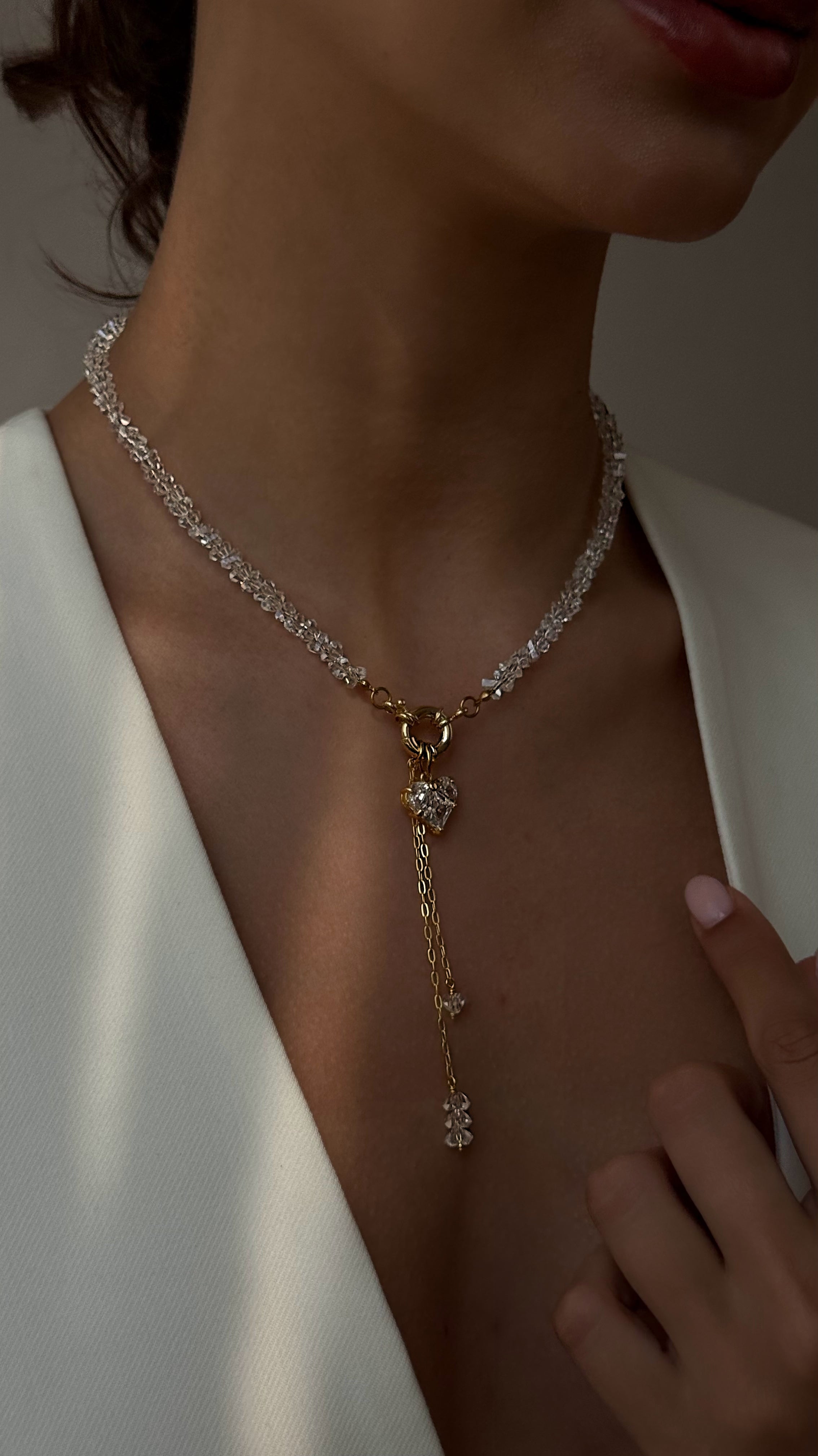 Close-up of a person wearing a delicate necklace with a white background