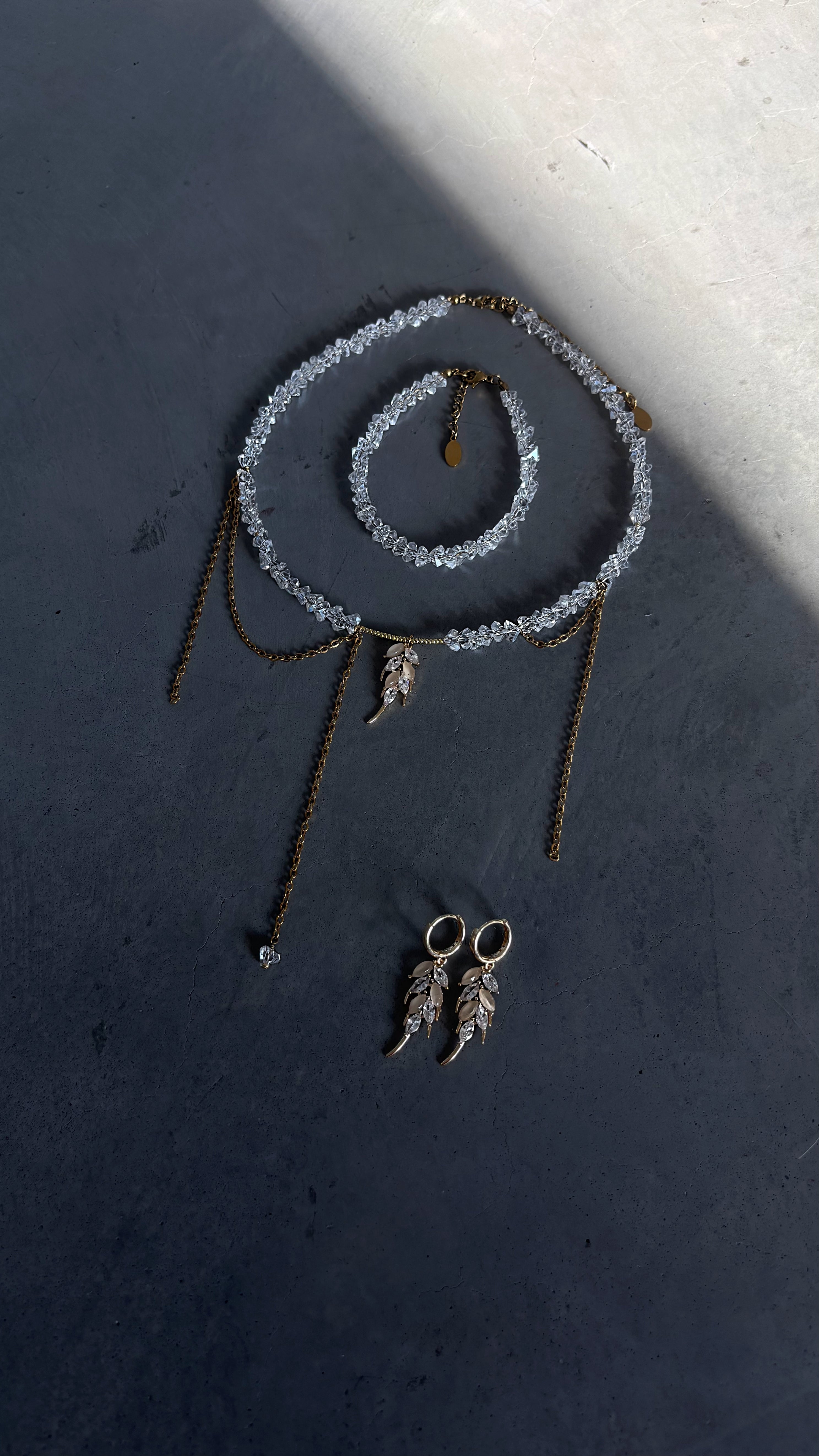 Necklace, bracelet and earrings on a dark surface