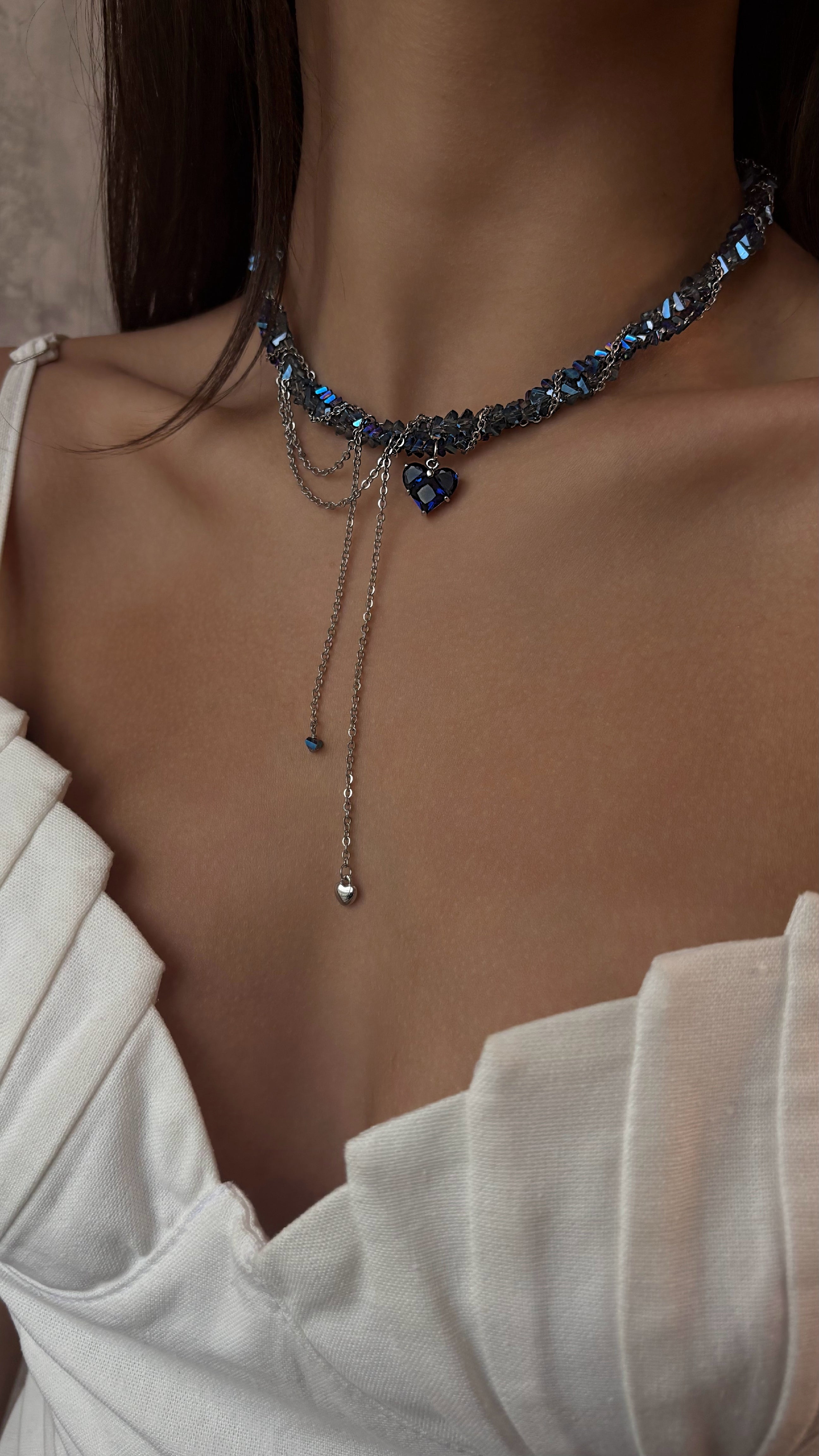 Necklace with blue crystal stones worn by a person in a white top