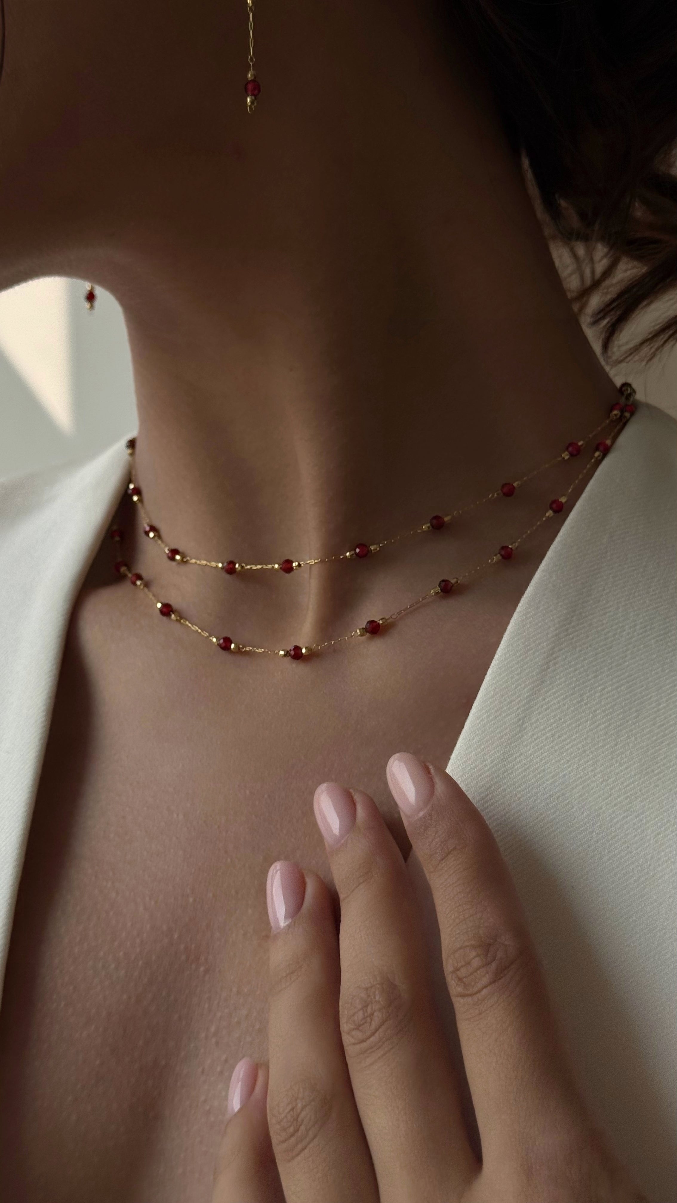 Necklace with red garnet worn by a person, with a blurred background