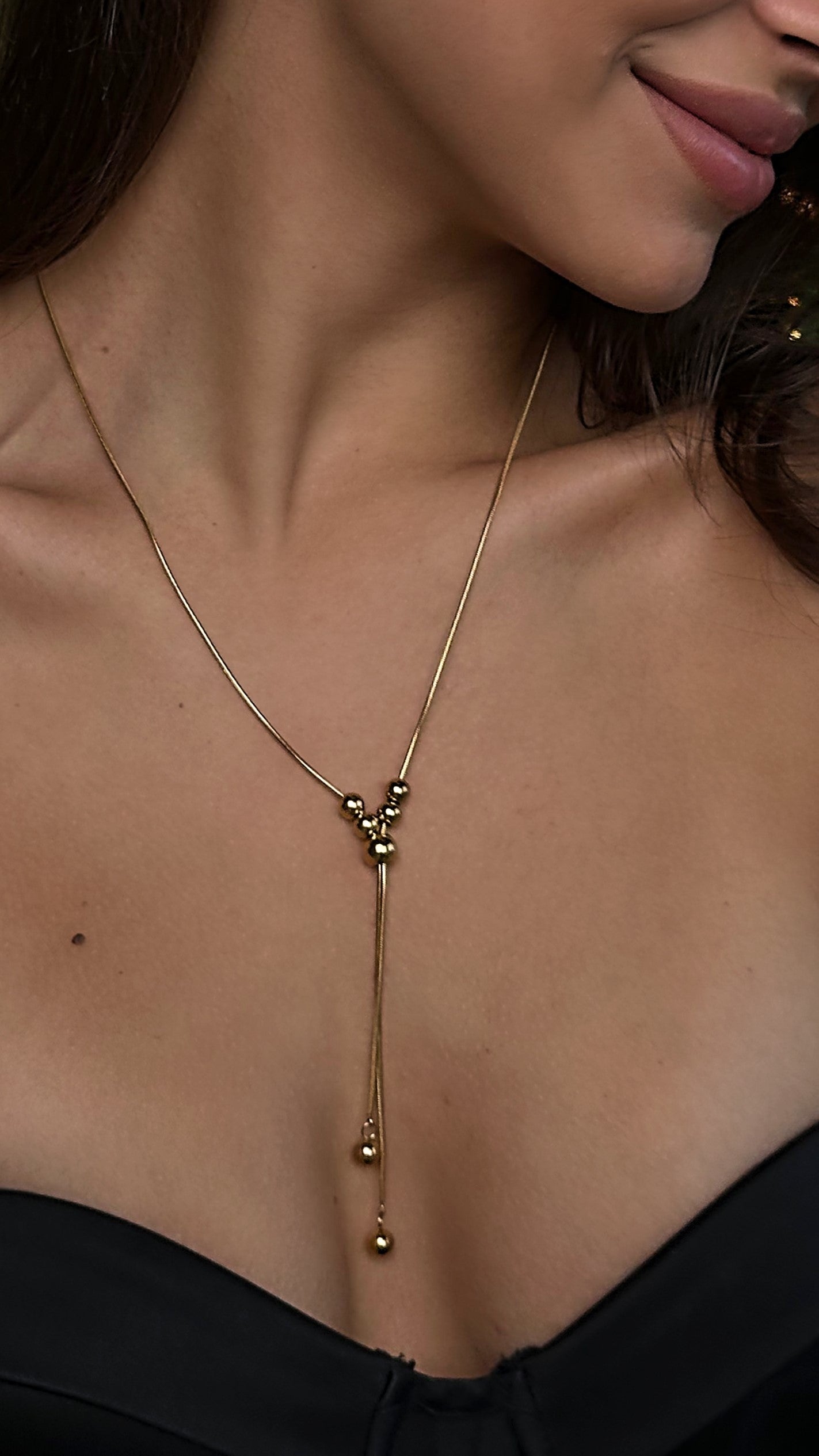 Trendy and versatile gold-tone lariat necklace with a front-facing slider, adjustable for multiple styling options, crafted from high-quality stainless steel for lasting shine.