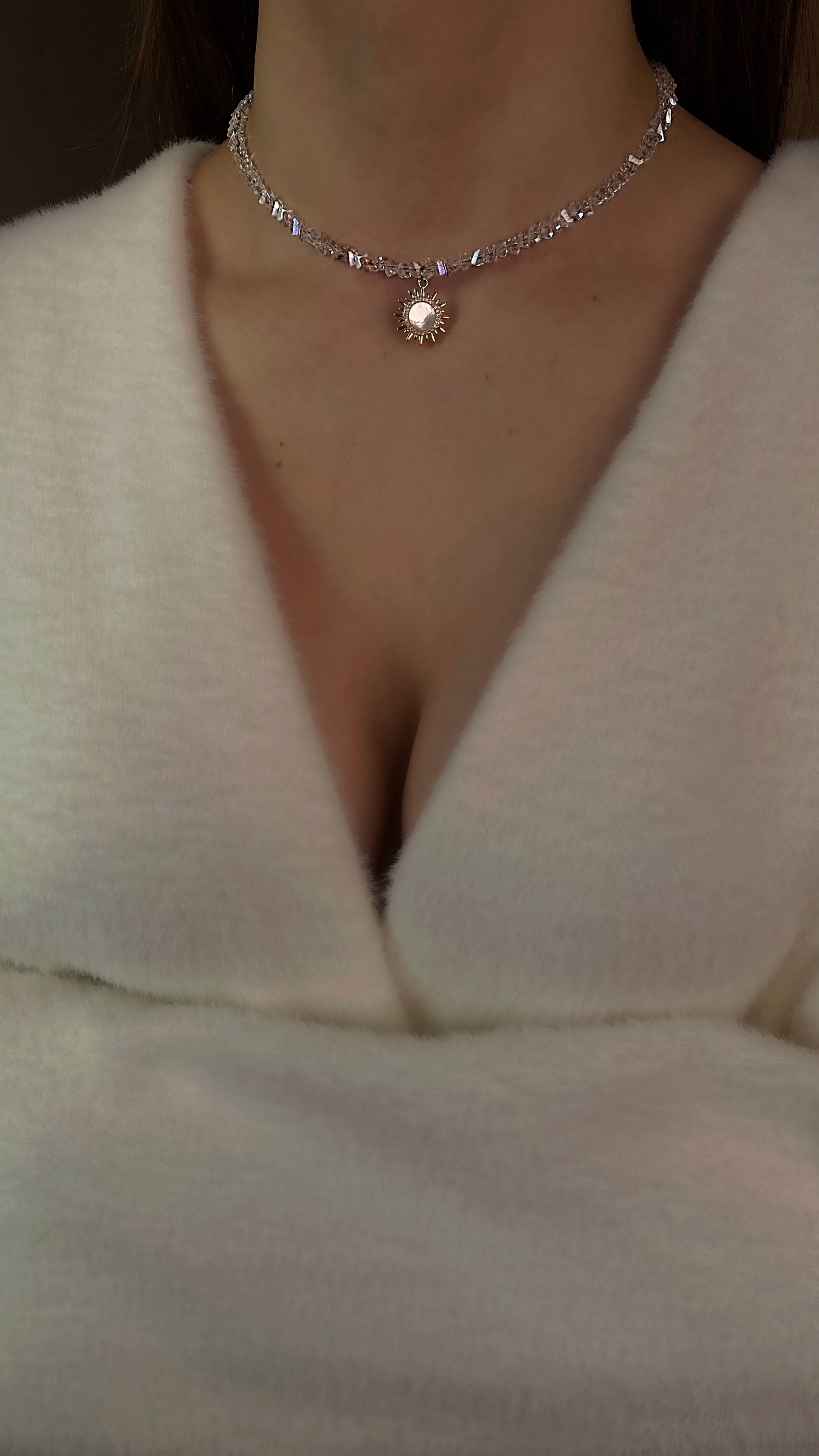 Necklace with a pendant worn by a person in a white garment