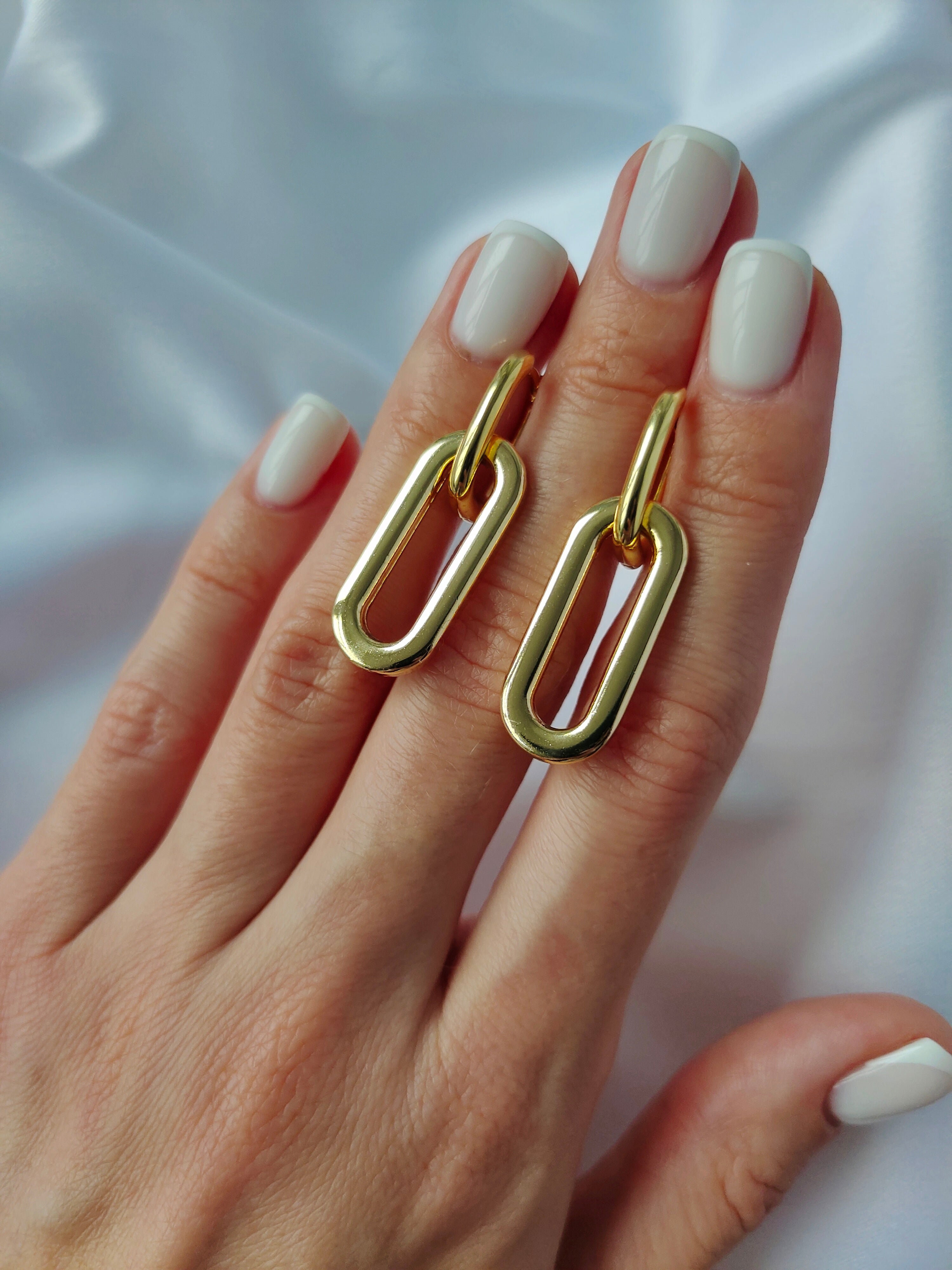 Minimalist dangle hoop earrings with two connected hoops forming a modern chain-like silhouette, available in gold and silver finishes. Lightweight and versatile, perfect for everyday wear or adding subtle elegance to special occasions.