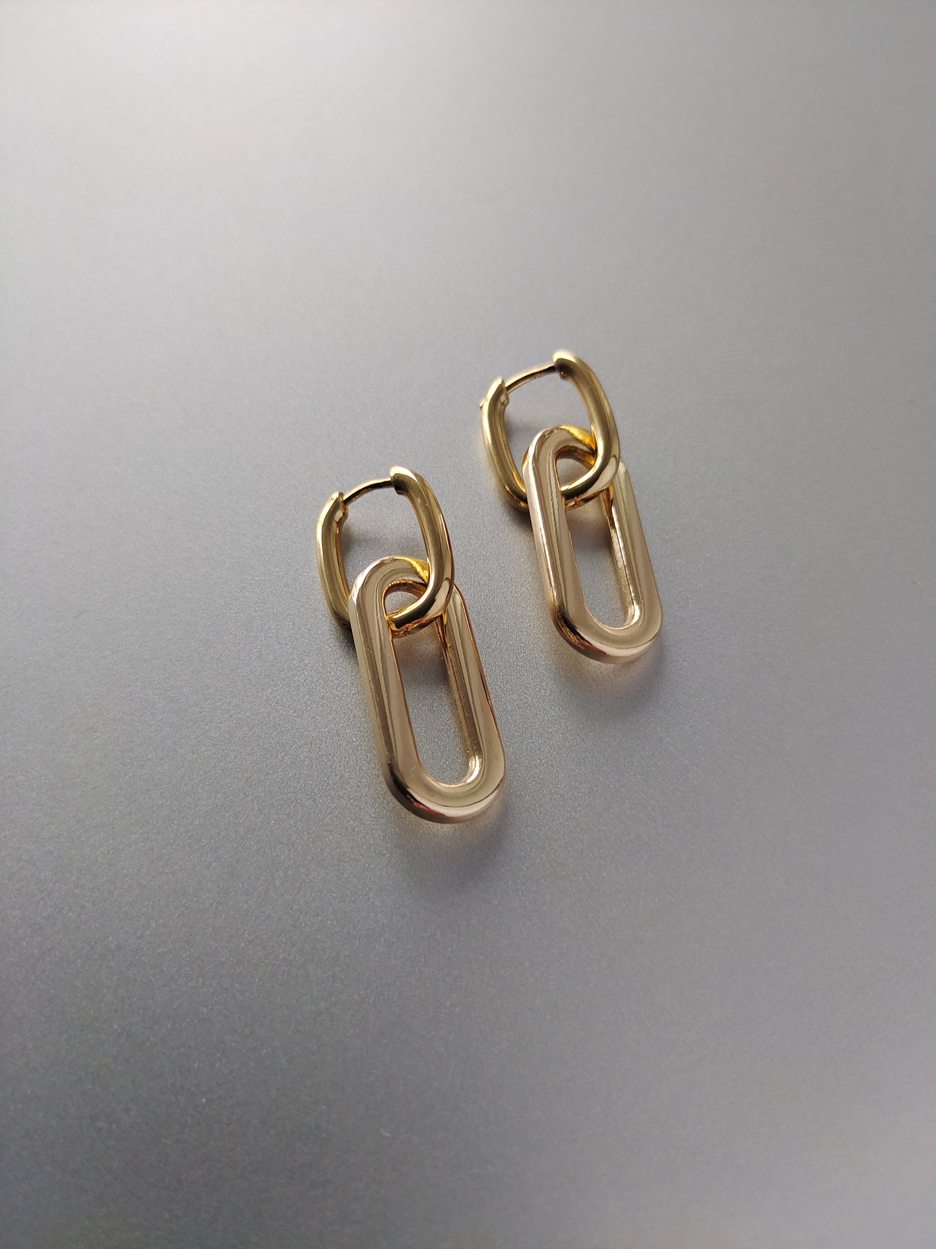 Gold-plated chain-style earrings on a gray background