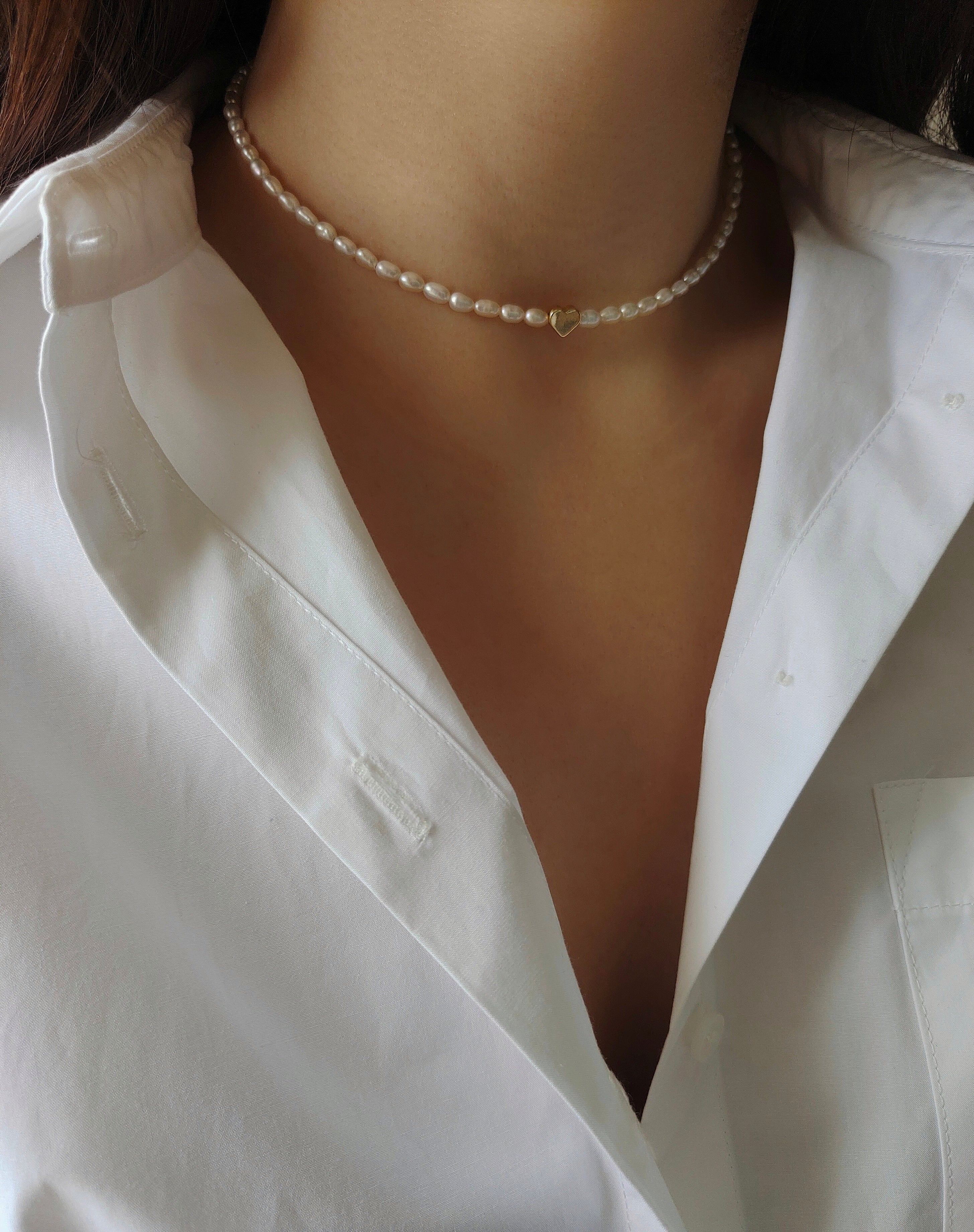 Pearl necklace worn by a person wearing a white shirt