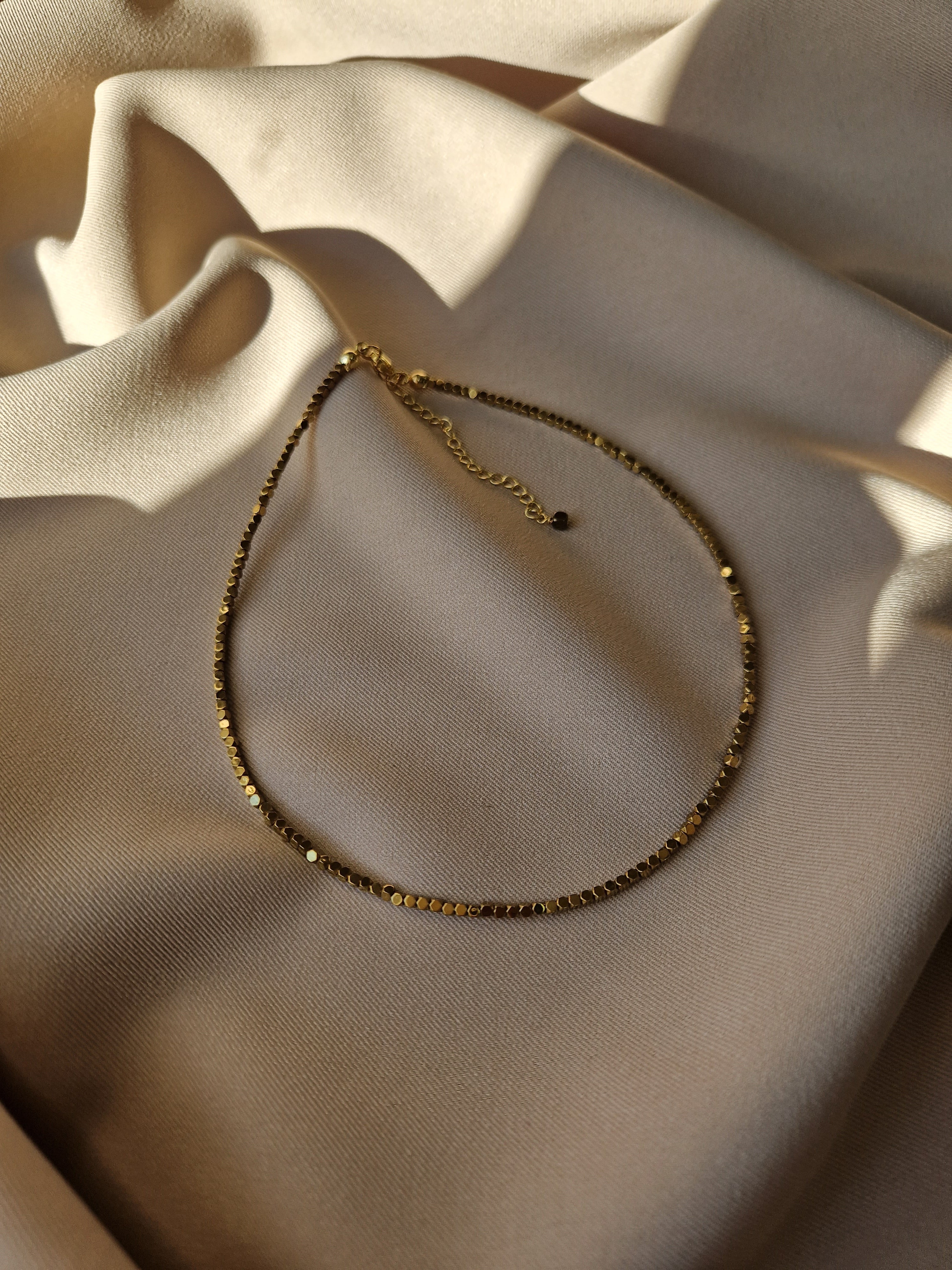 Minimalist hematite choker featuring natural hematite beads and gold-tone jewelry-grade stainless steel, combining sleek elegance with modern design for everyday wear.
