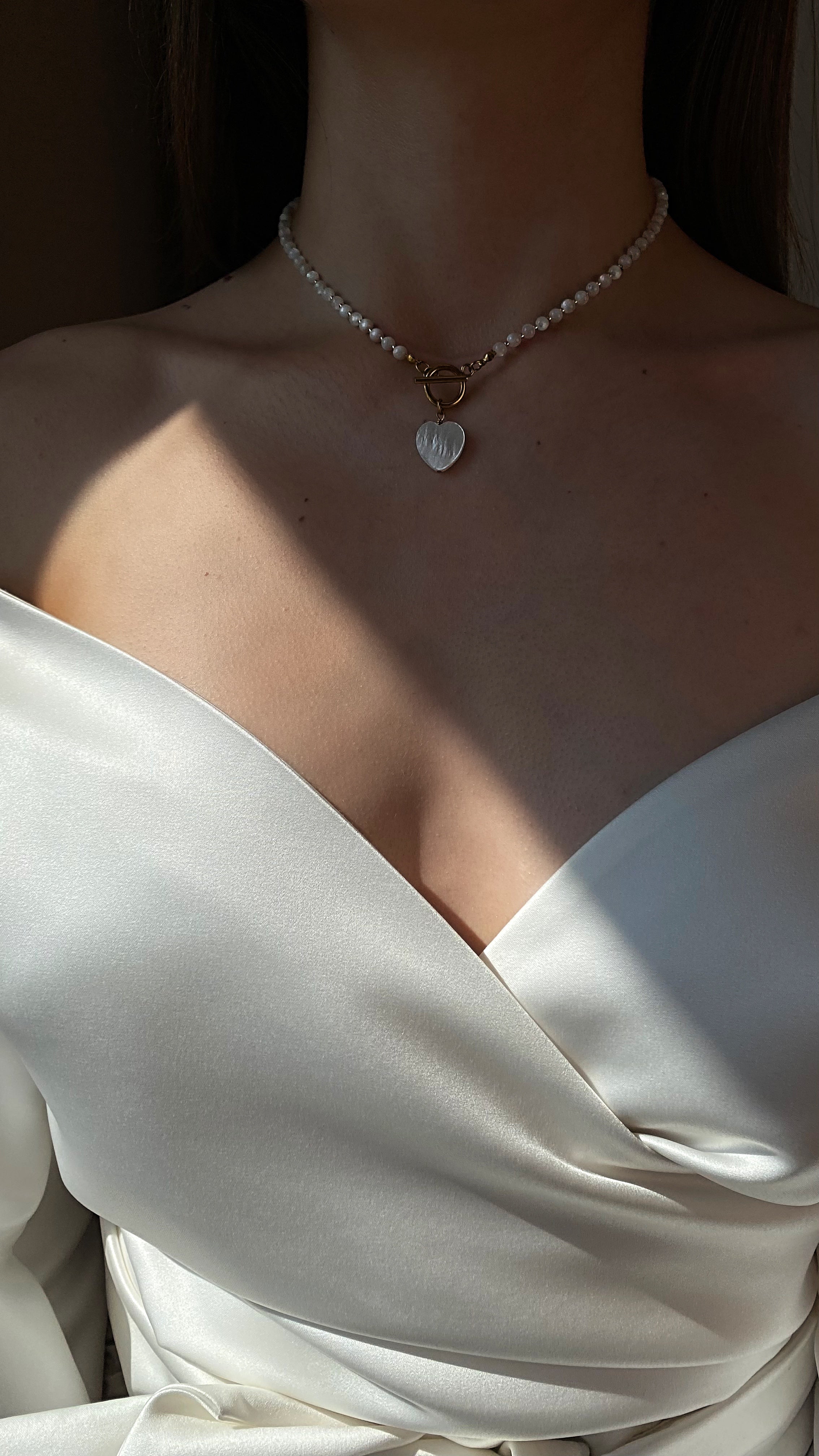 Elegant necklace with genuine white mother-of-pearl beads, a heart-shaped mother-of-pearl pendant, and a gold-tone stainless steel clasp, offering natural shimmer and refined style
