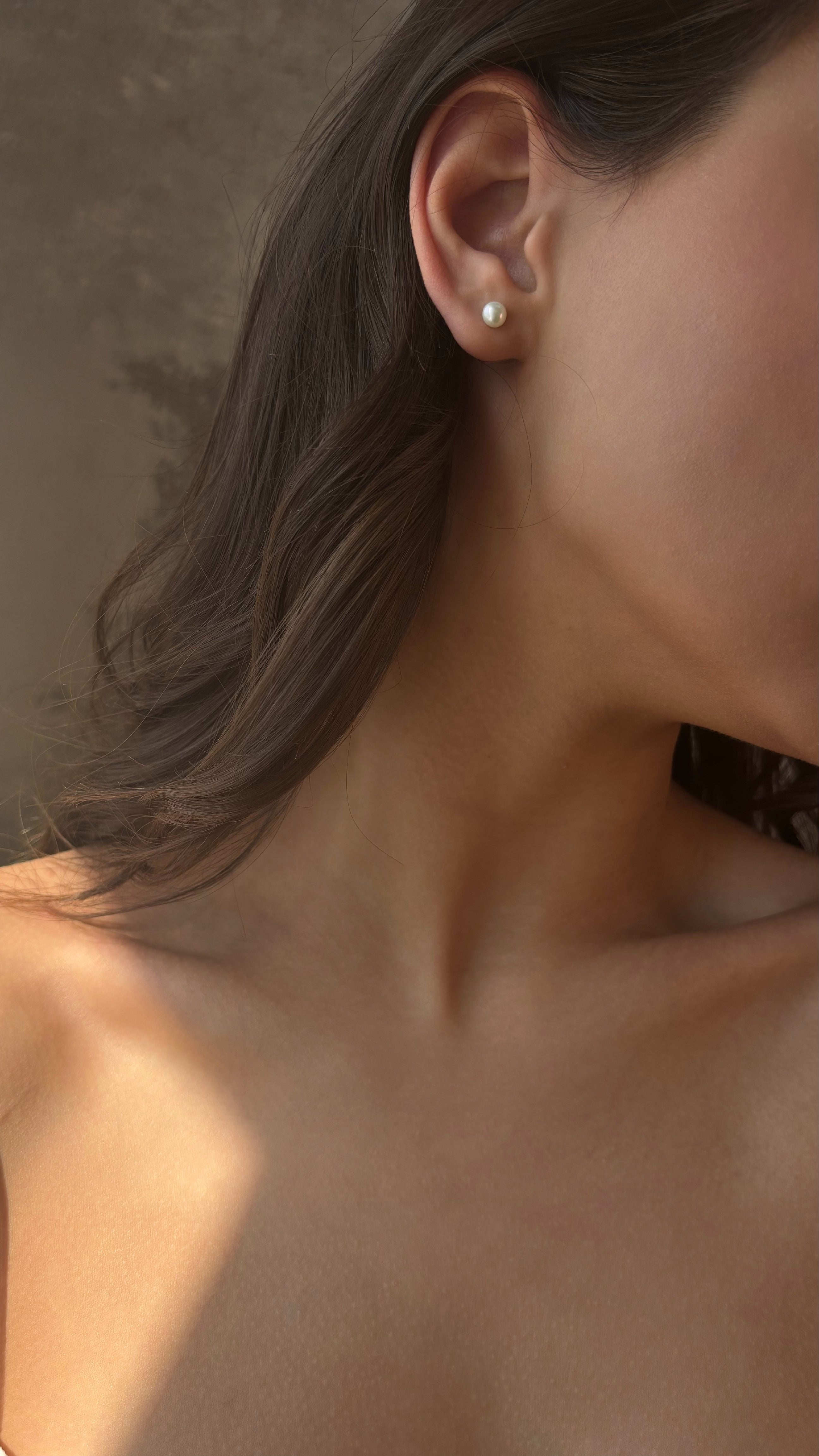 Close-up of a person wearing a small earring with a neutral background