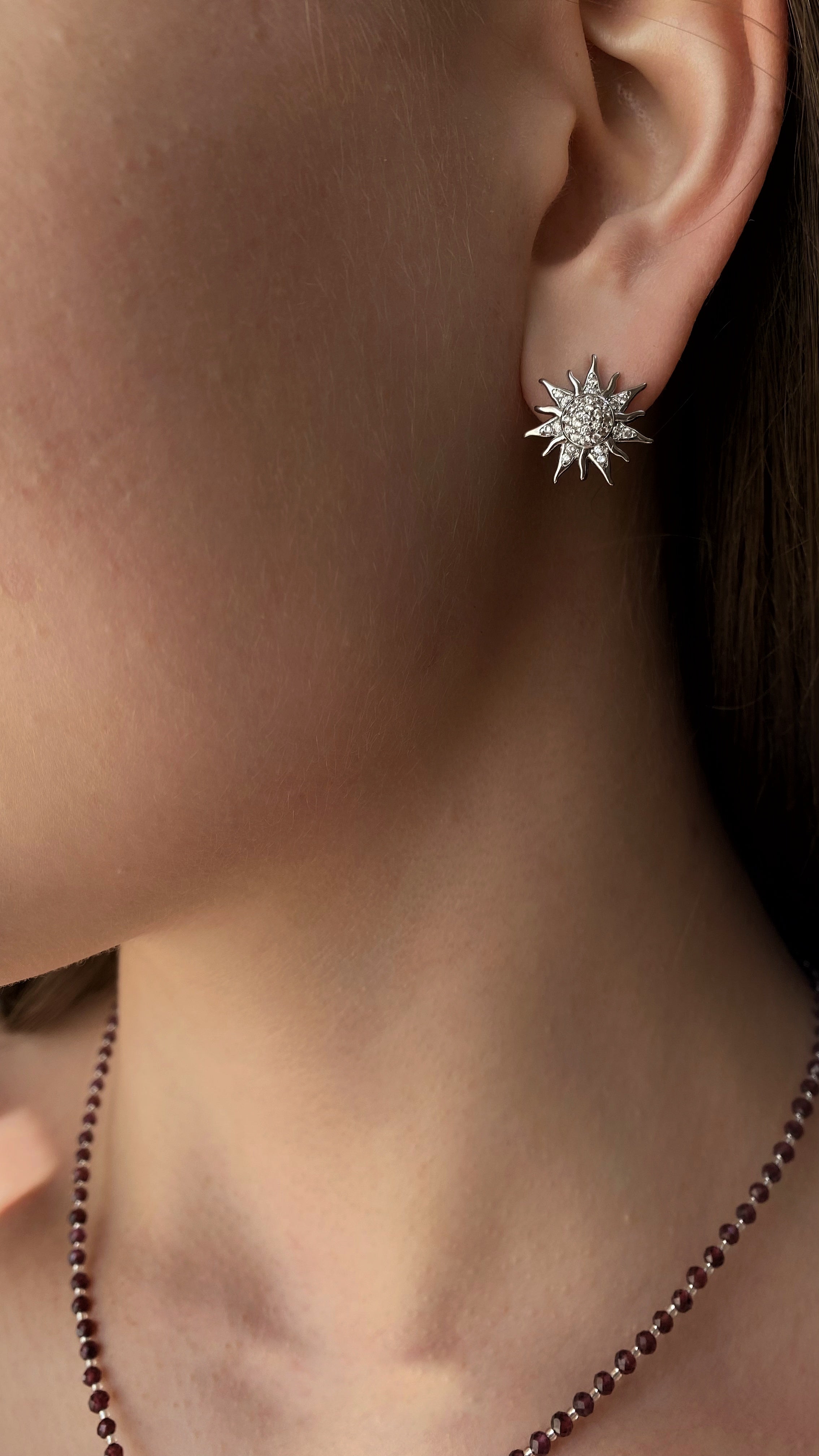 Pair of sun-shaped earrings on a beige fabric background