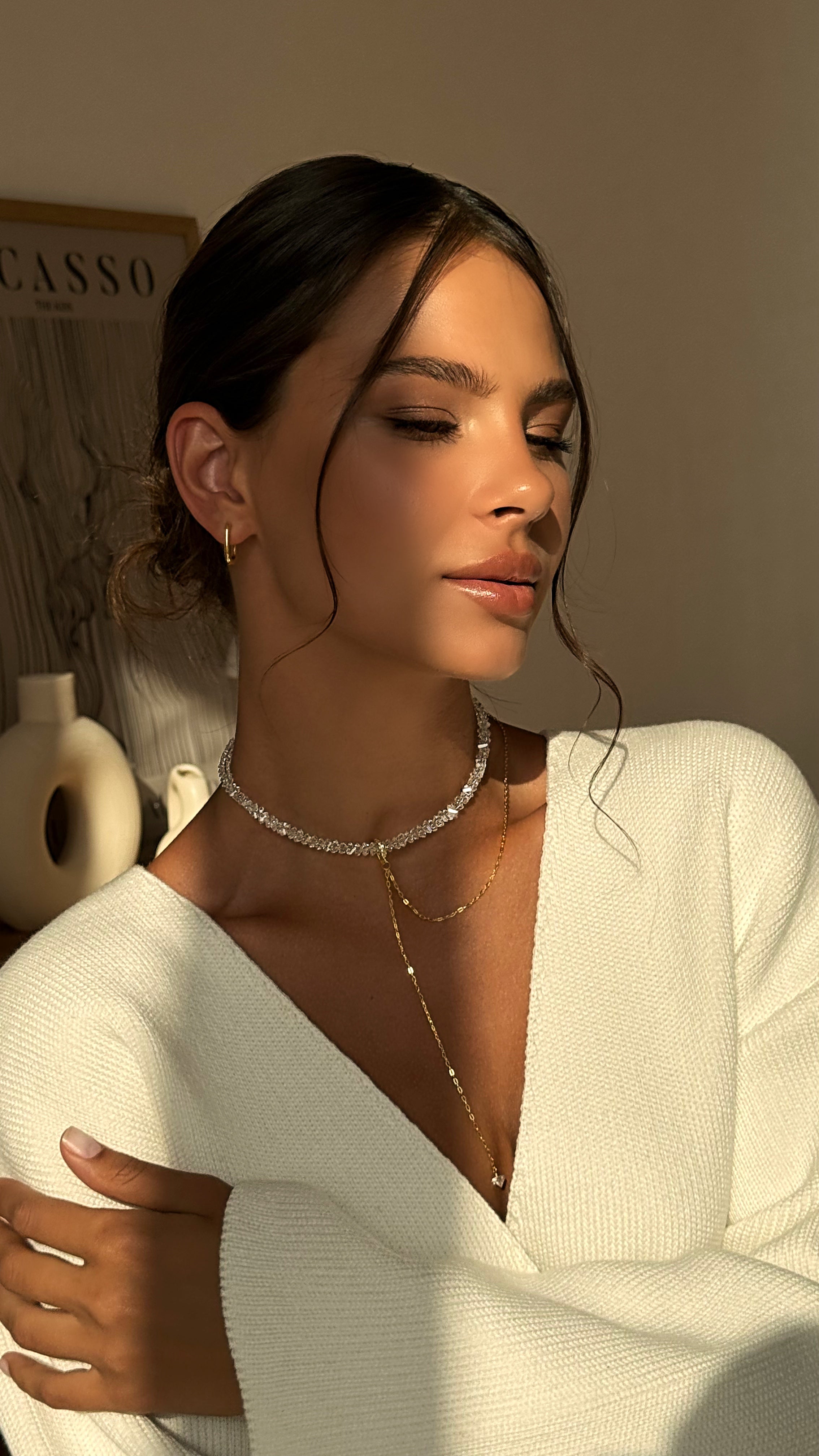 Woman wearing a white top and necklace with a neutral background