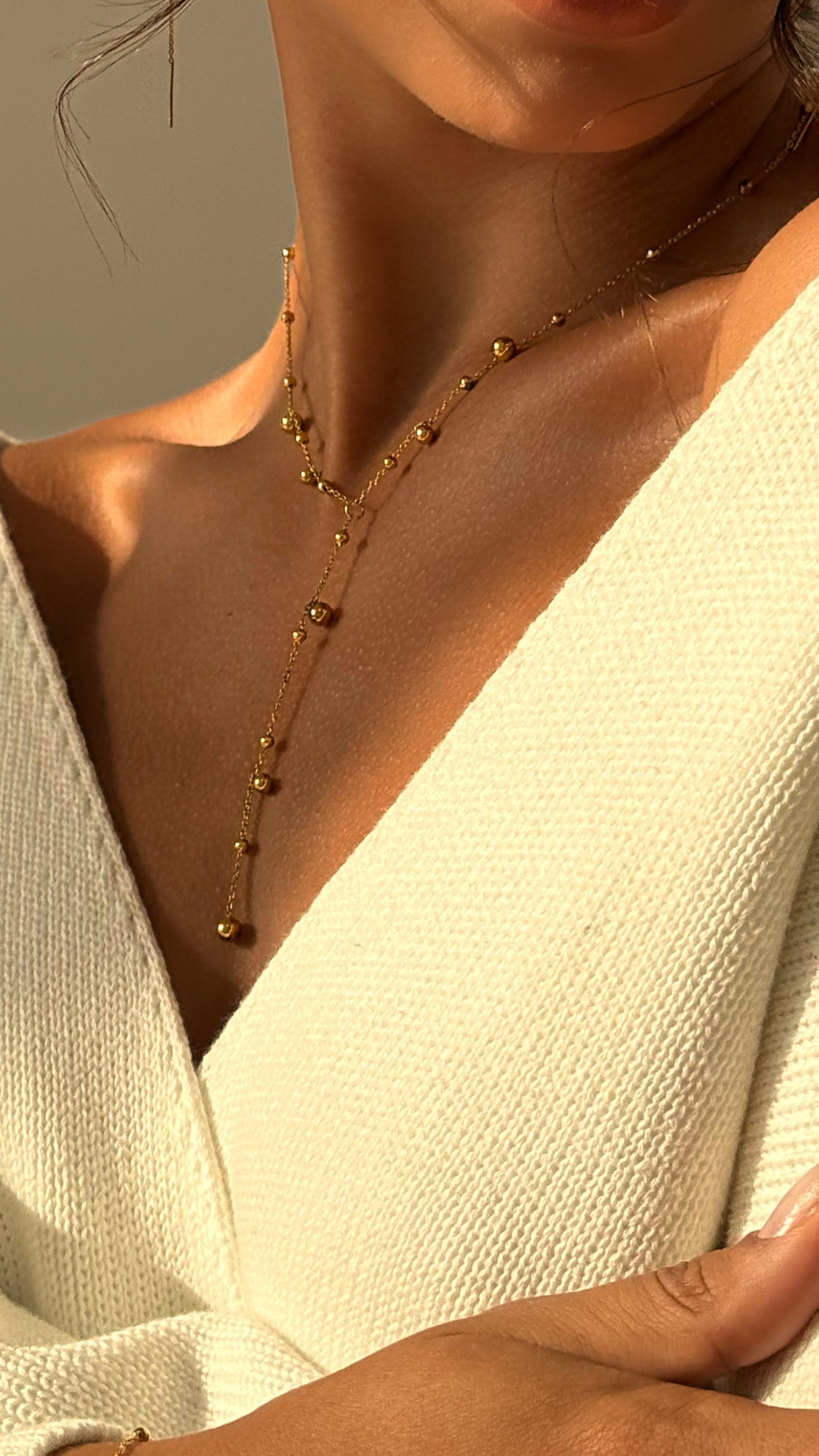 Close-up of a gold-plated necklace on a person wearing a white top.