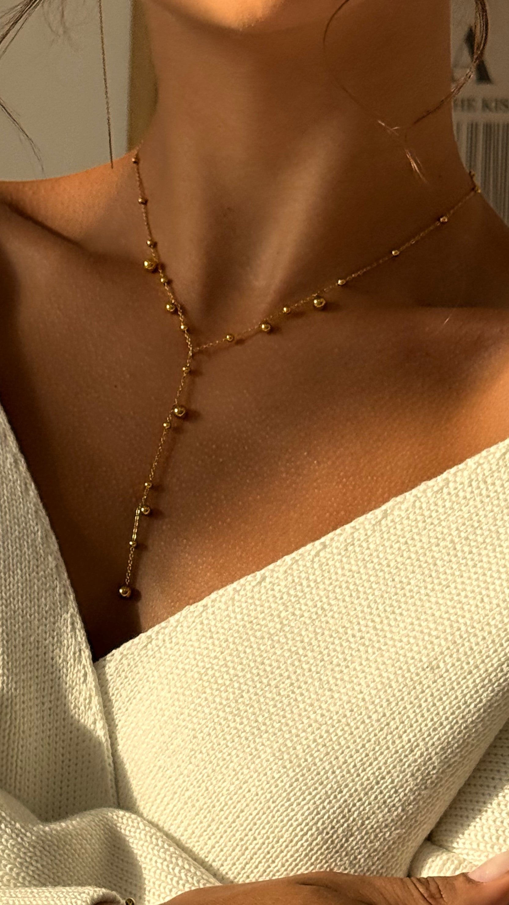 Gold-plated necklace on a person wearing a white top