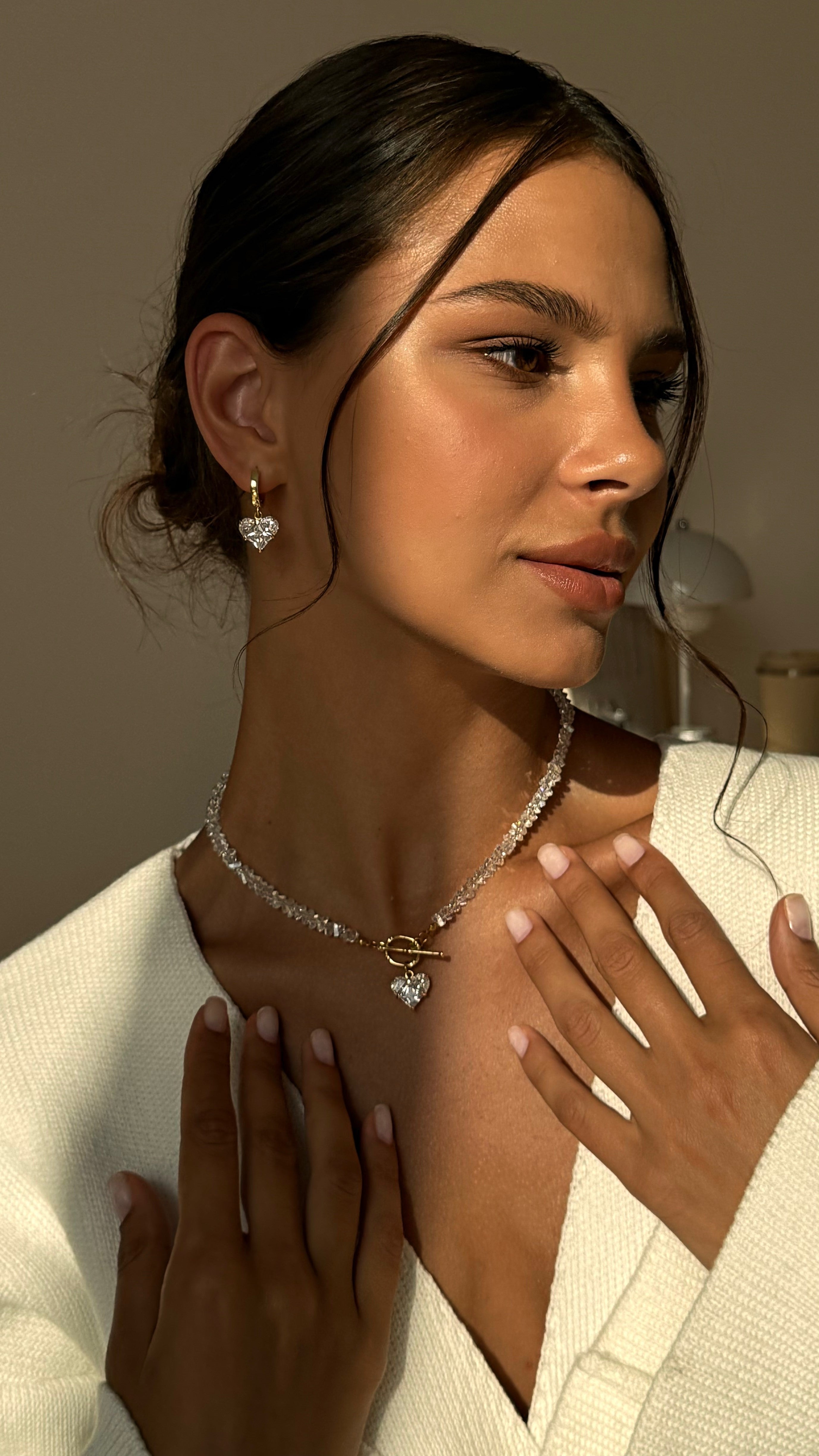 Woman wearing a necklace and earrings with a neutral background
