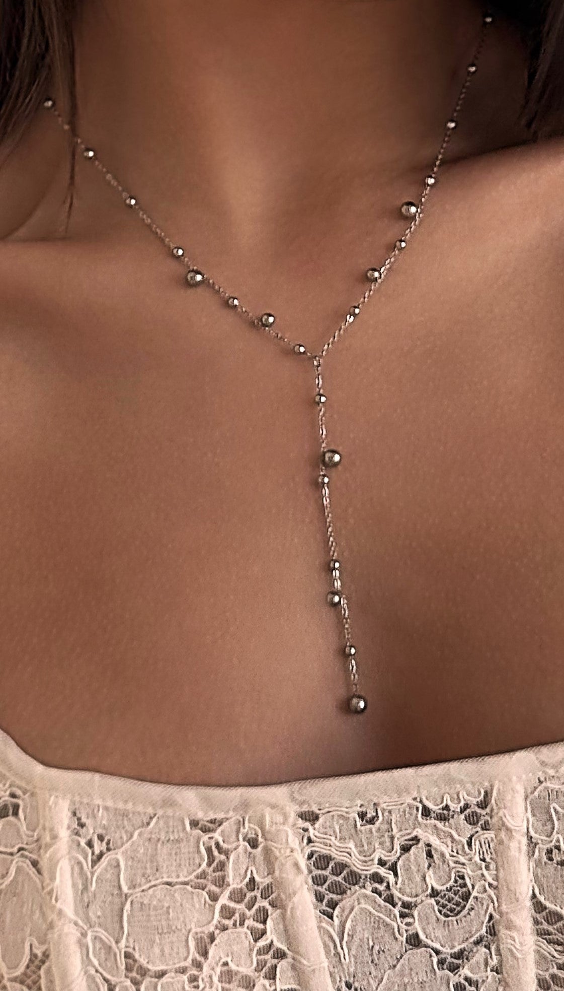 Sleek silver-tone lariat necklace with stainless steel beads in varying sizes, offering a minimalist and contemporary accent for both casual and elegant looks.