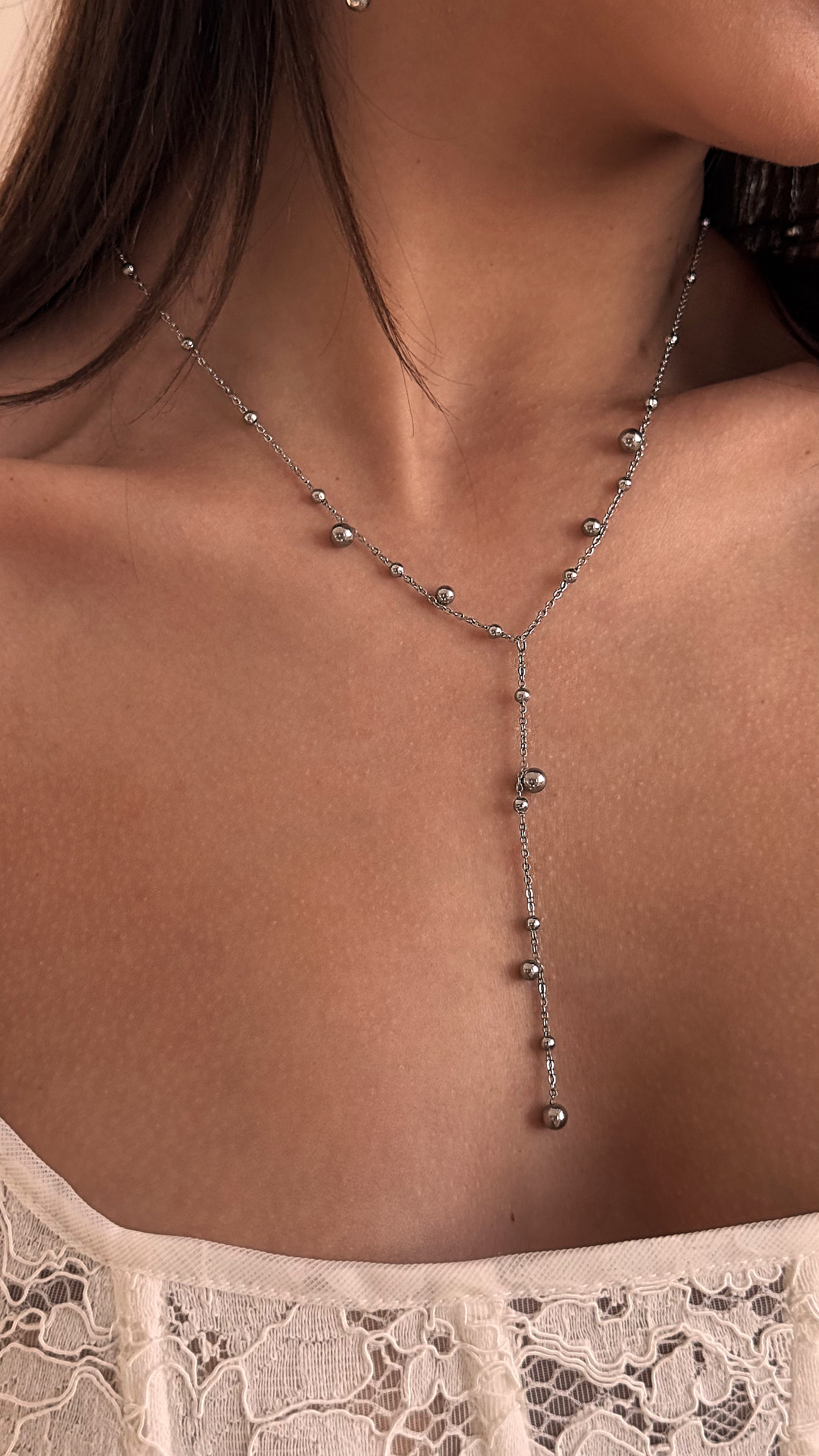 Sleek silver-tone lariat necklace with stainless steel beads in varying sizes, offering a minimalist and contemporary accent for both casual and elegant looks.