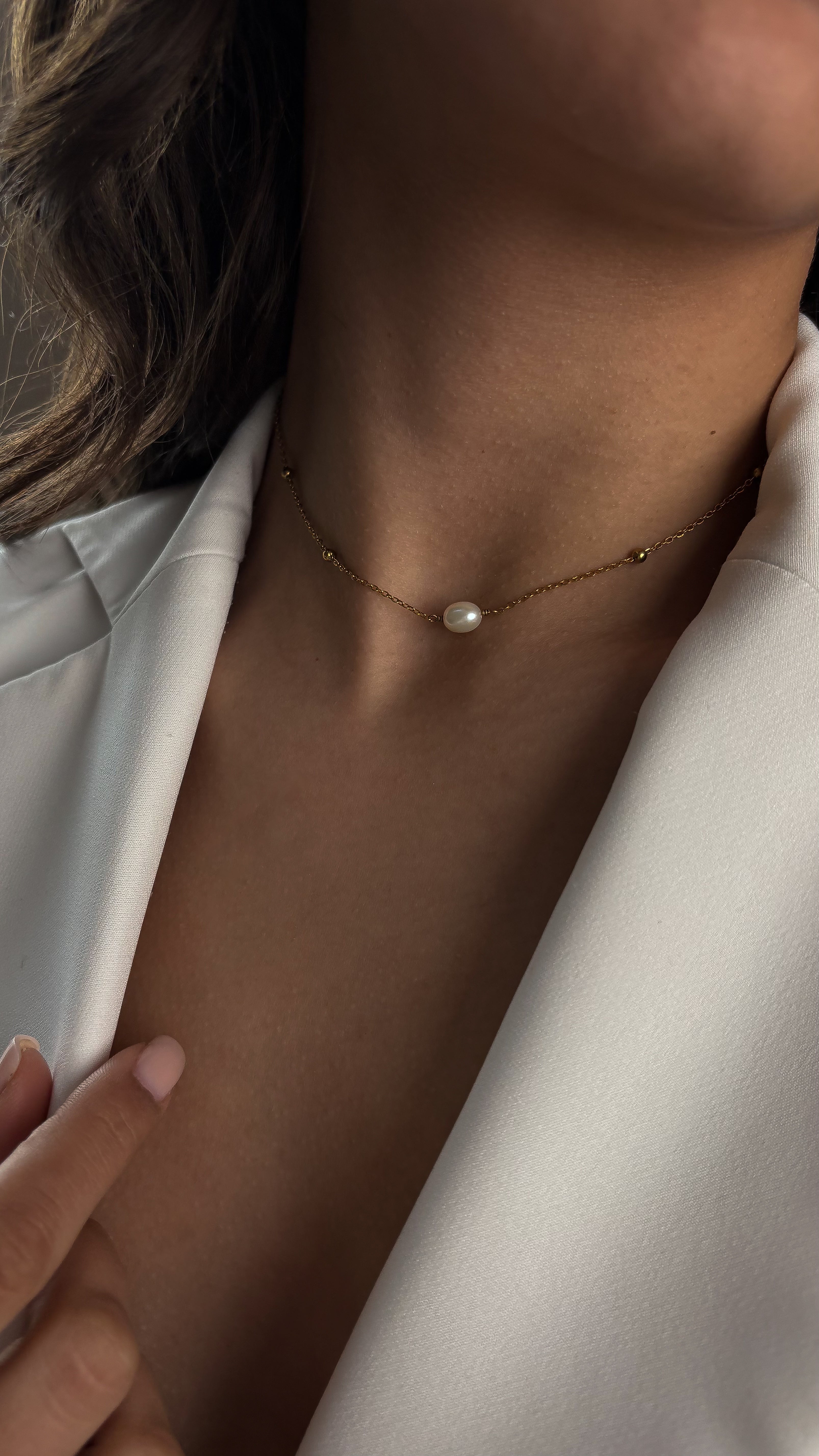 Pearl necklace worn by a person with a neutral background