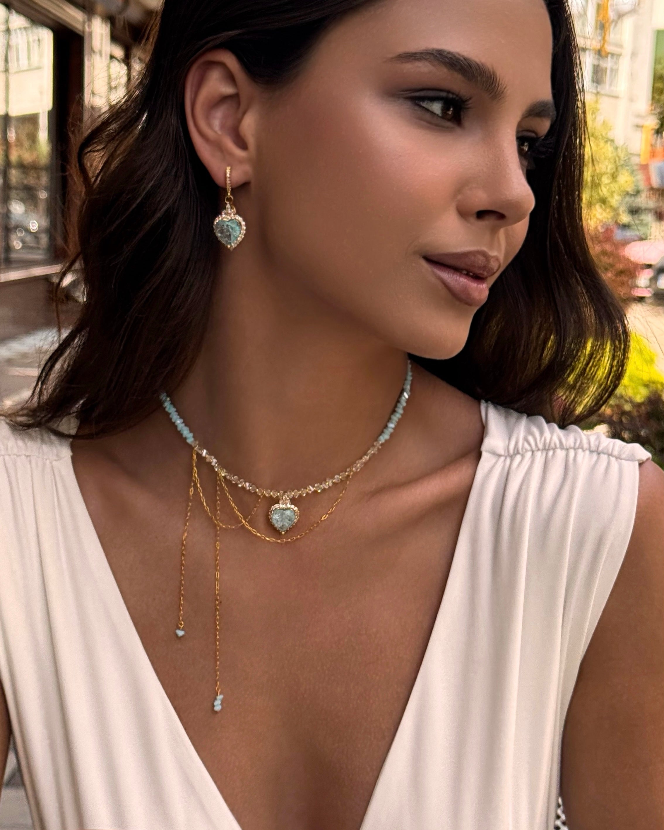 Woman wearing a necklace and earrings with a blurred outdoor background