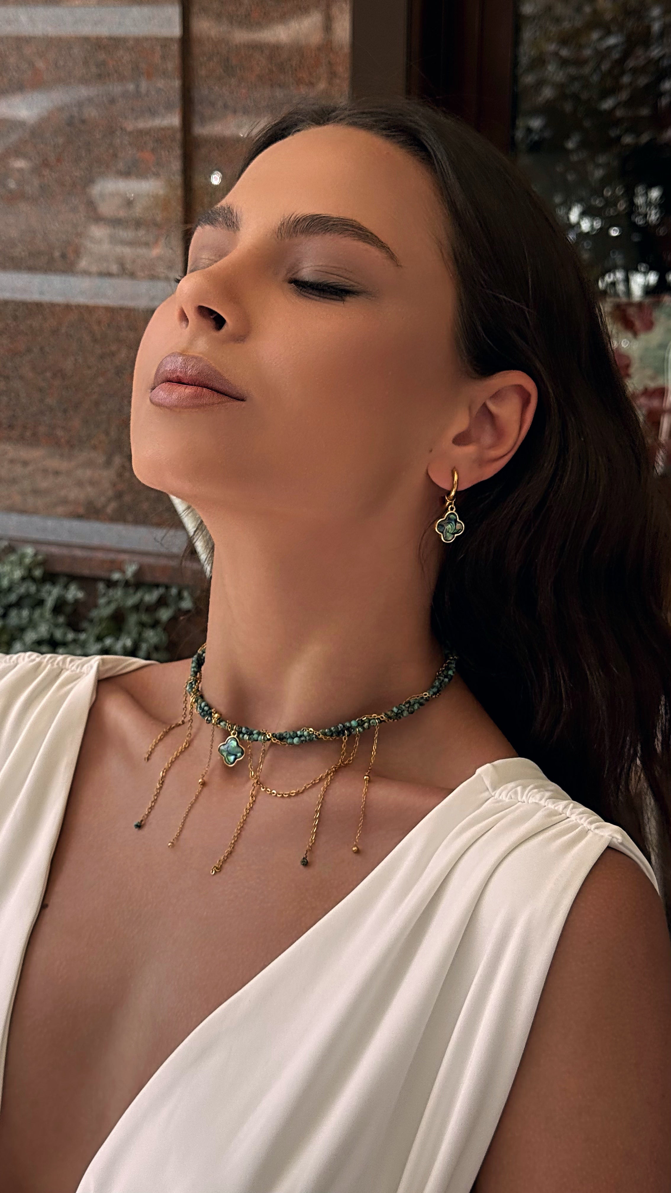 Woman wearing a necklace and earrings with a blurred background