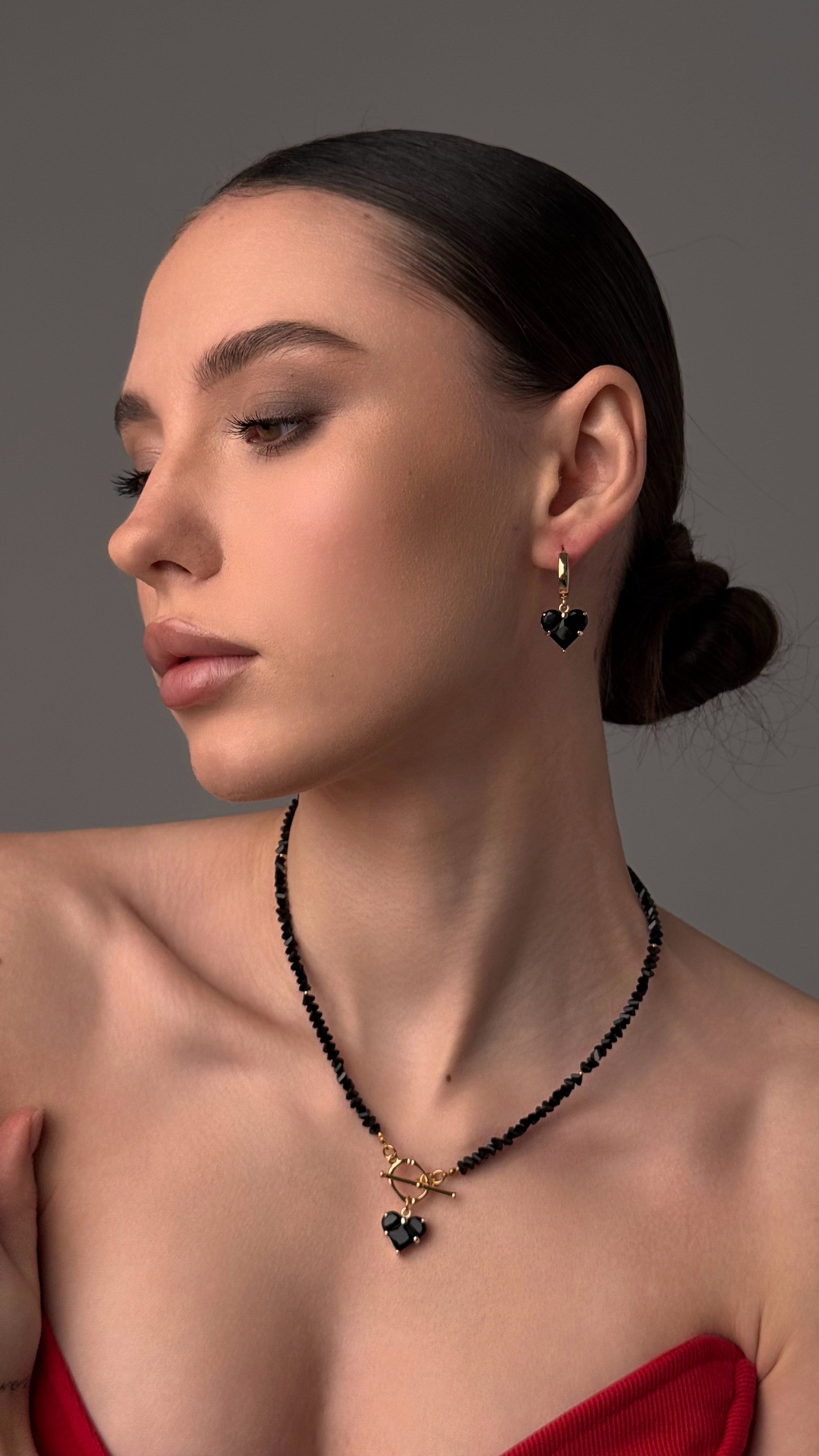 Woman wearing a black beaded necklace and earrings against a gray background