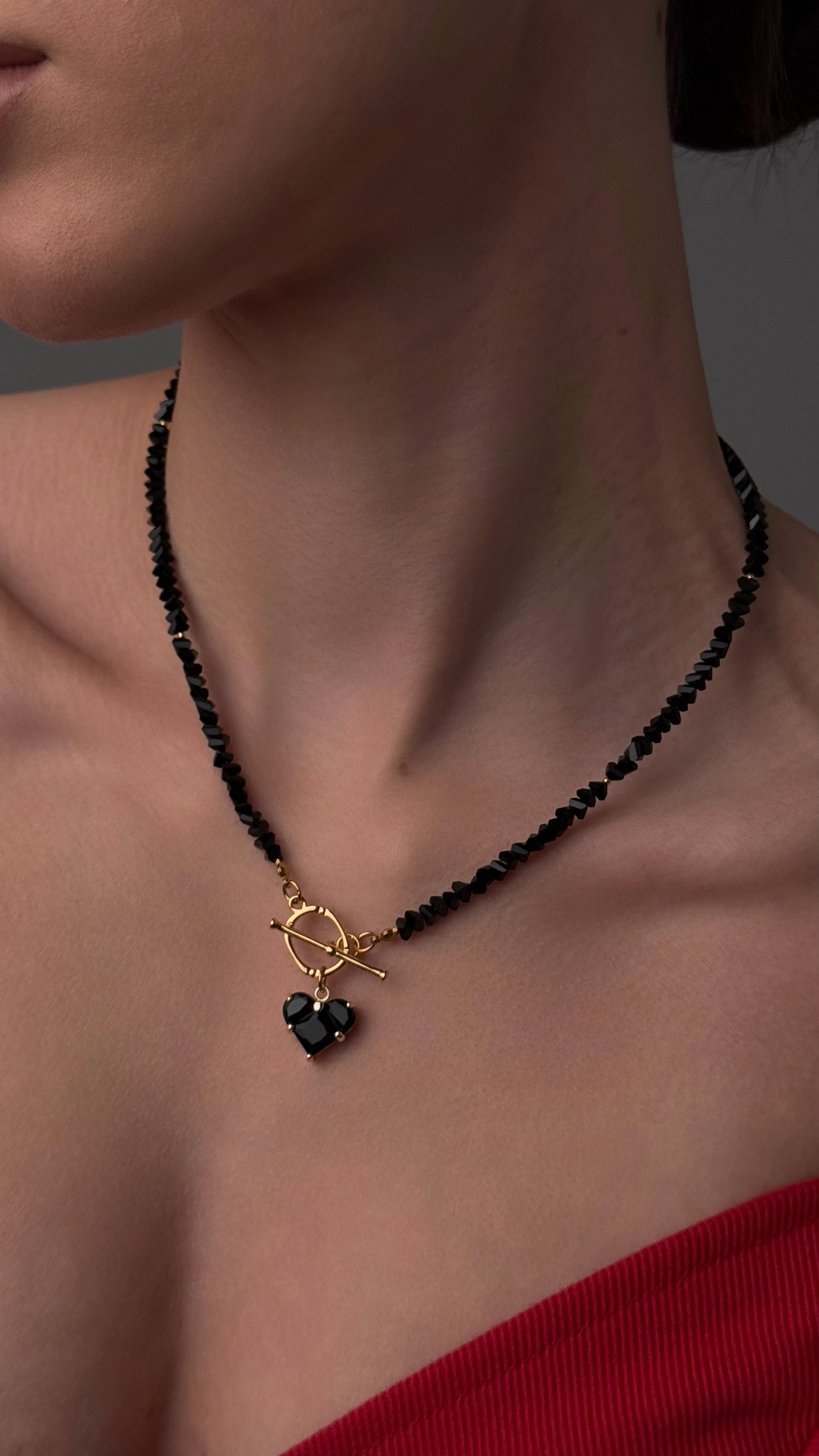Woman wearing a black beaded necklace against a gray background