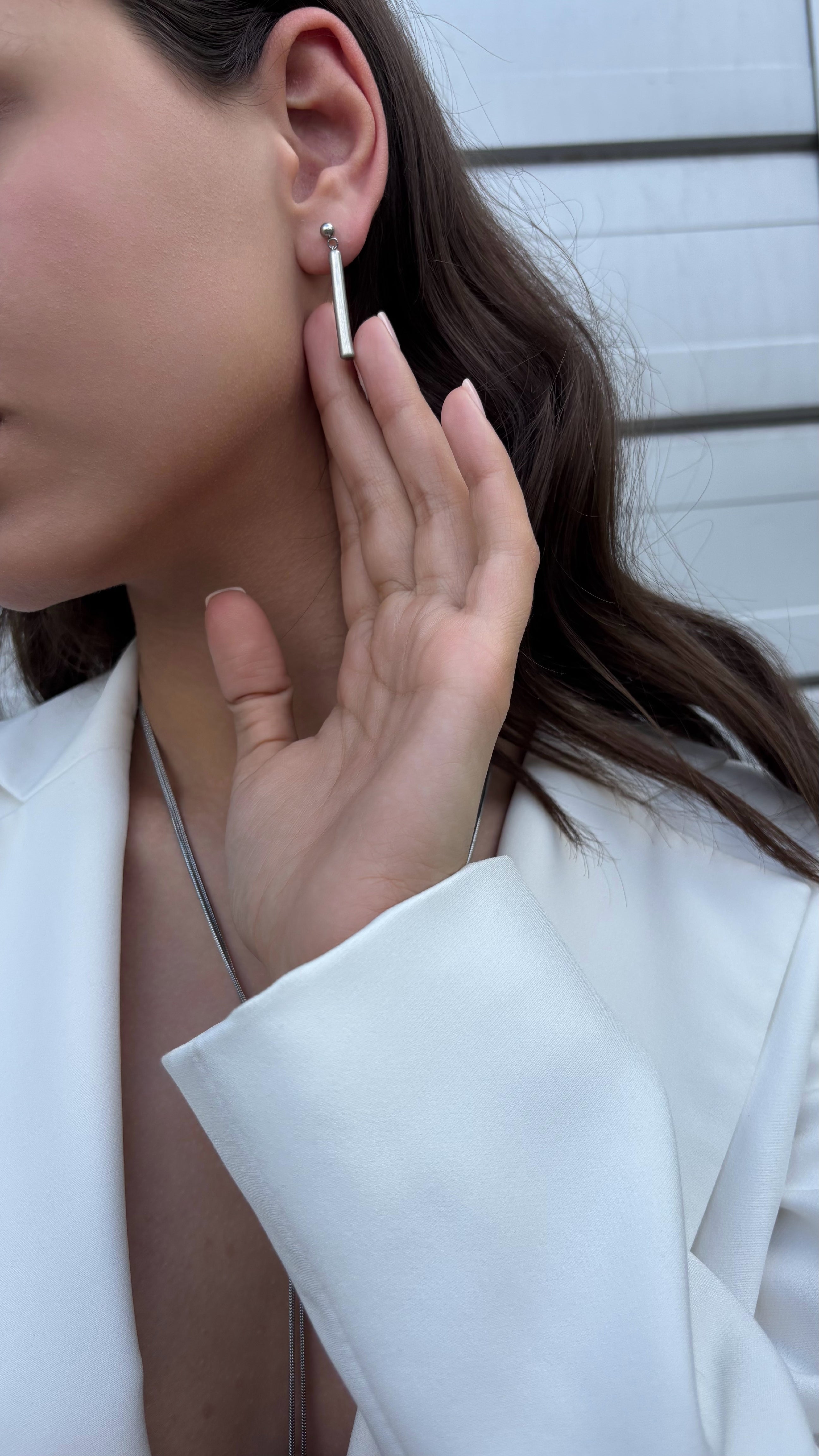 Close-up of a person wearing a silver-tone earring with a blurred background
