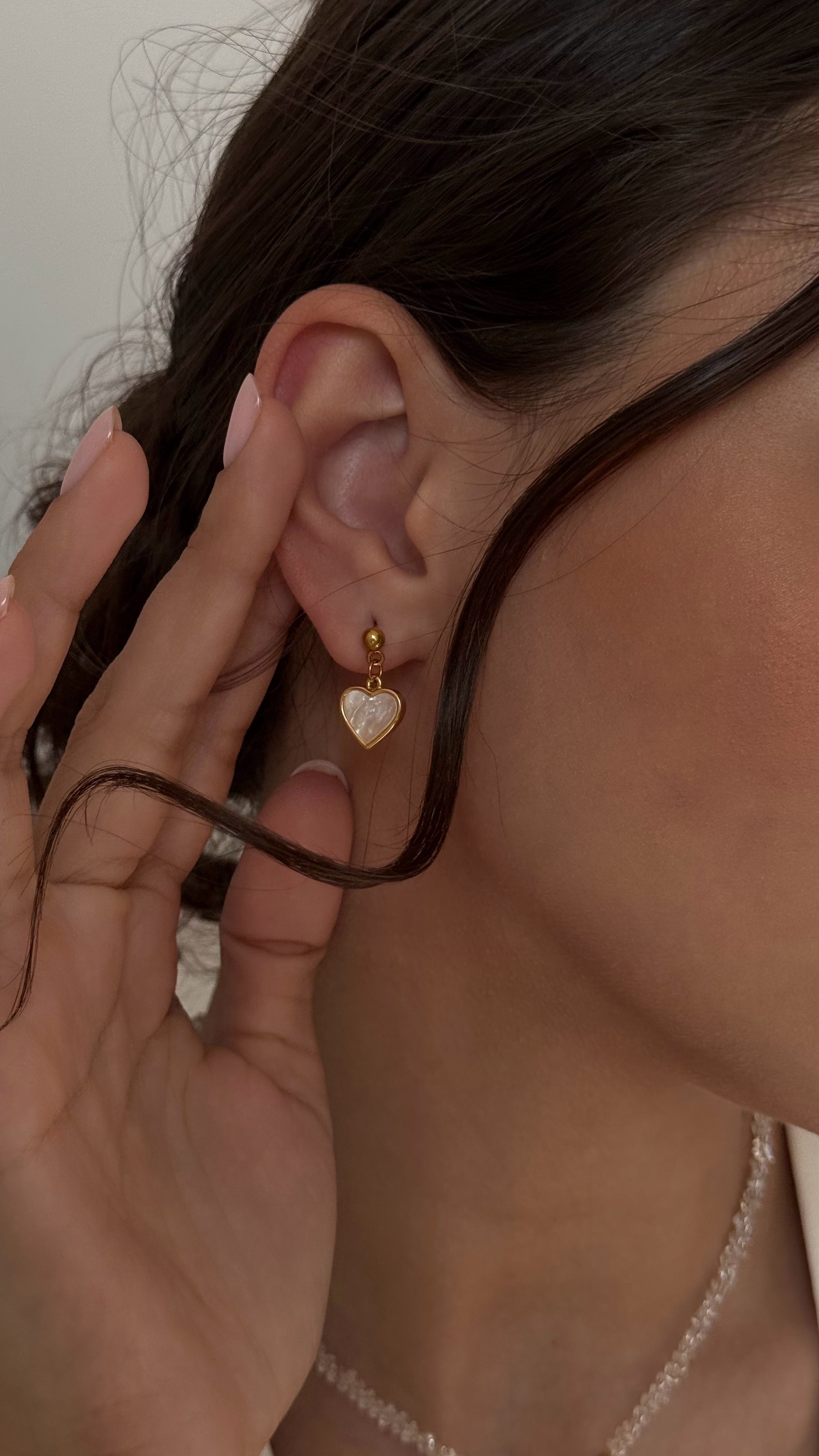 Delicate stud earrings with mother-of-pearl heart charms, offering a romantic and feminine touch with minimalist design and soft shimmer.